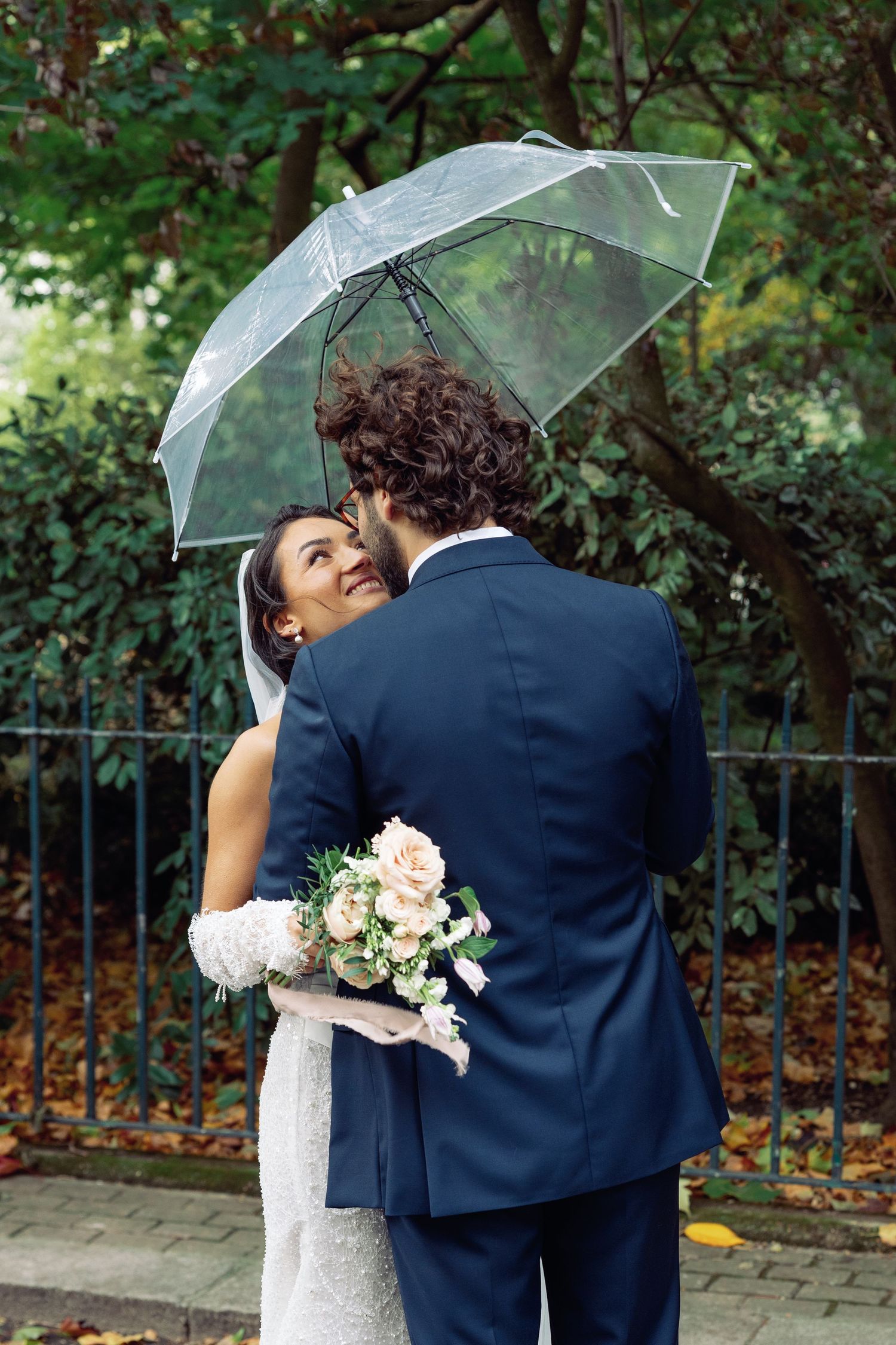 Wedding photo sequence under clear umbrellas with autumn foliage in background.