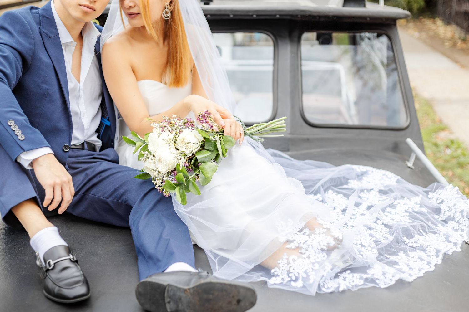 Bride and groom share intimate moment on vintage car during fall wedding photography session.