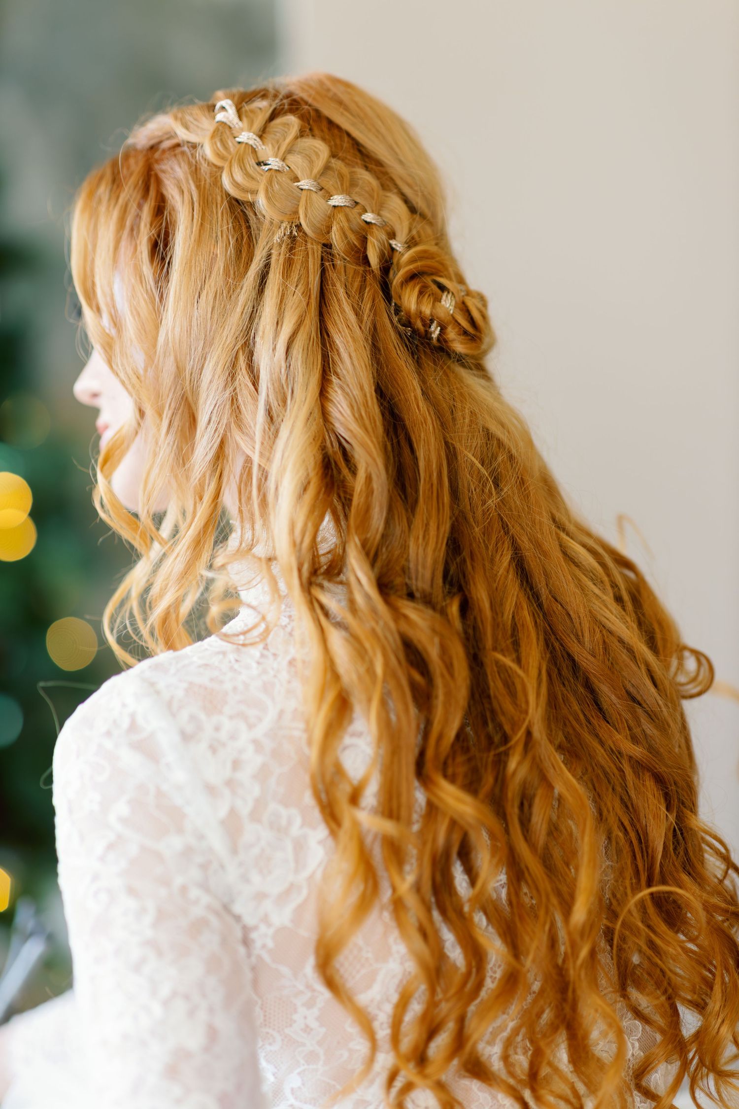 Close-up of intricate braided hairstyle with blonde waves against light background.