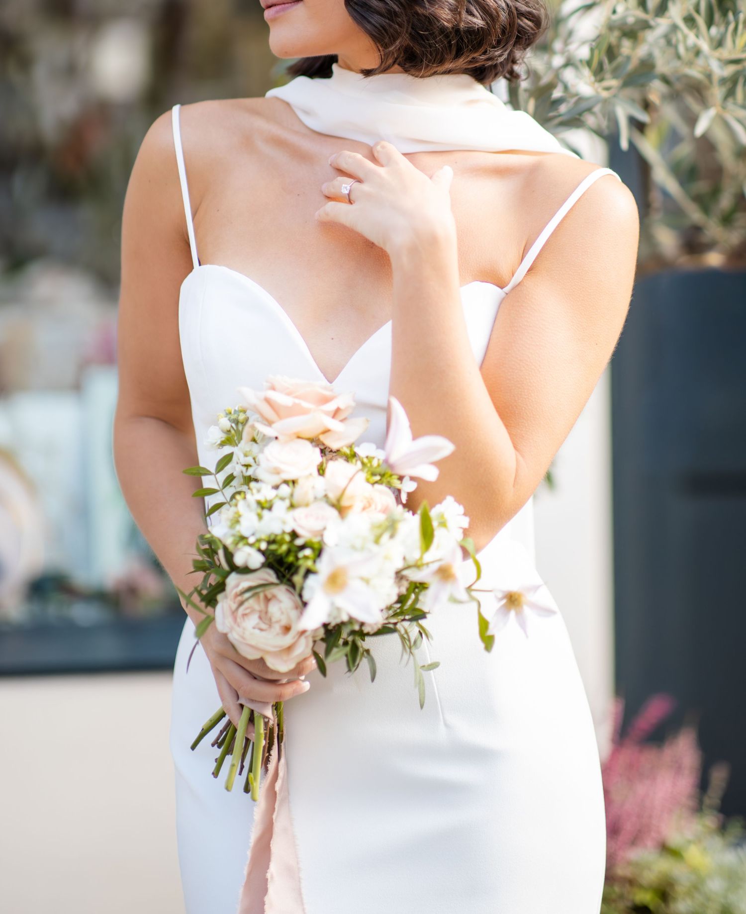 Delicate details of white wedding dress and floral bouquet.