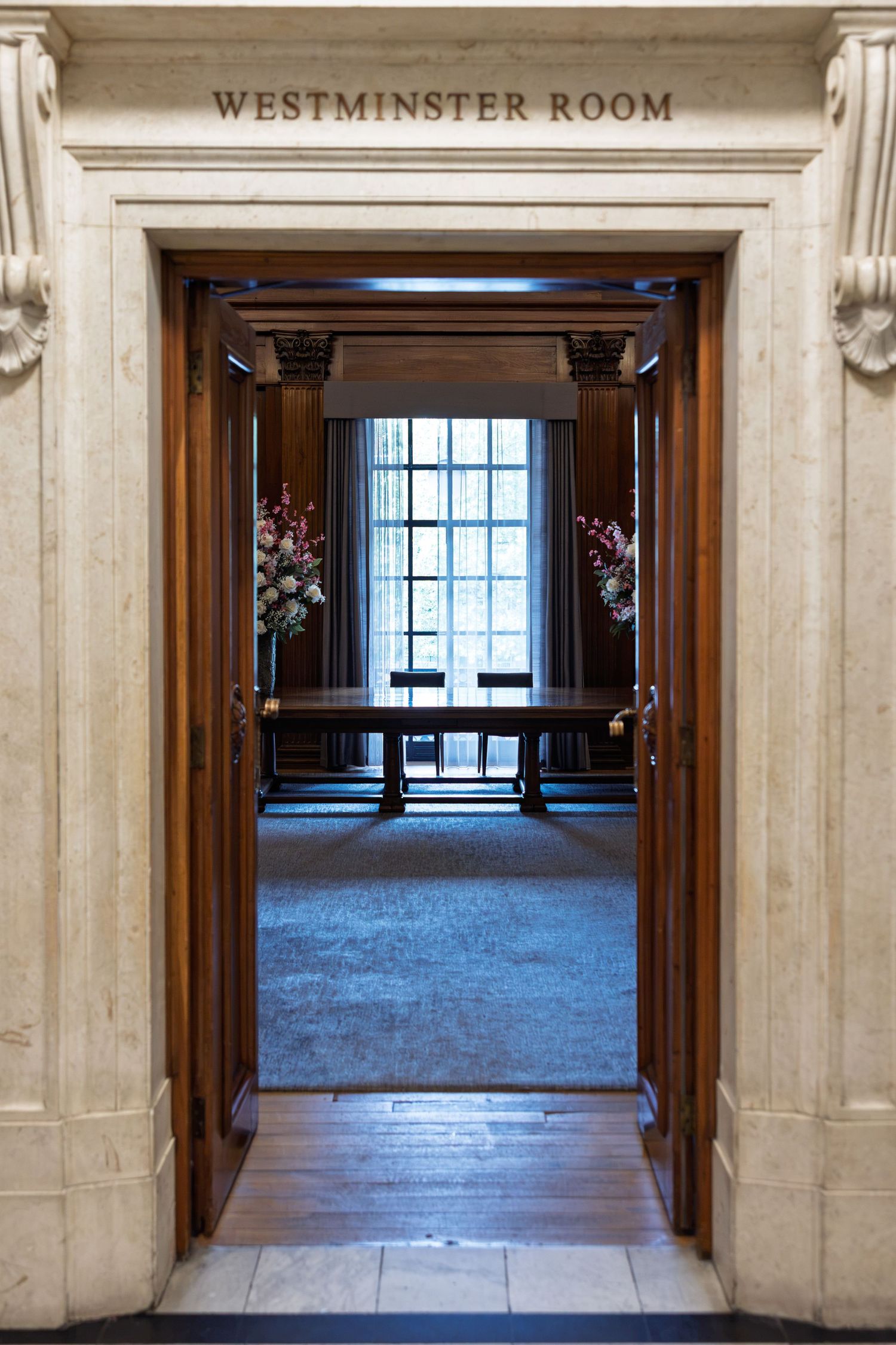 Elegant entrance to the Westminster Room with wooden doors, floral arrangements, and grand stone archway.