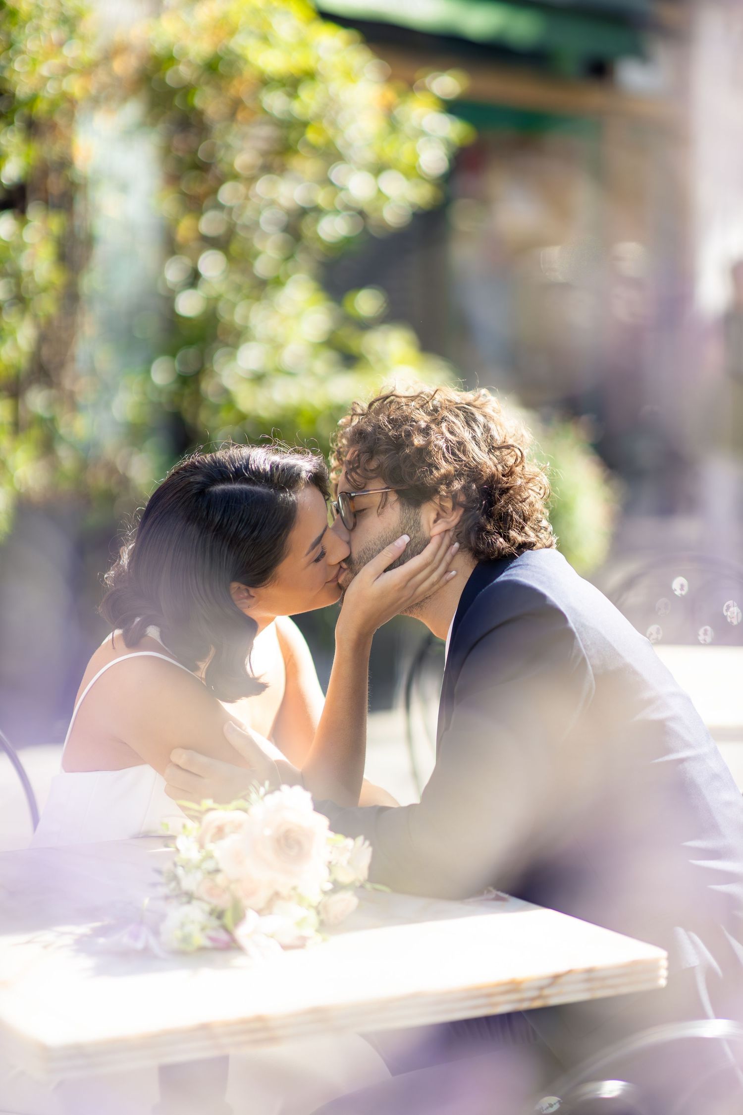 A romantic moment between newlyweds in a sunlit outdoor setting.