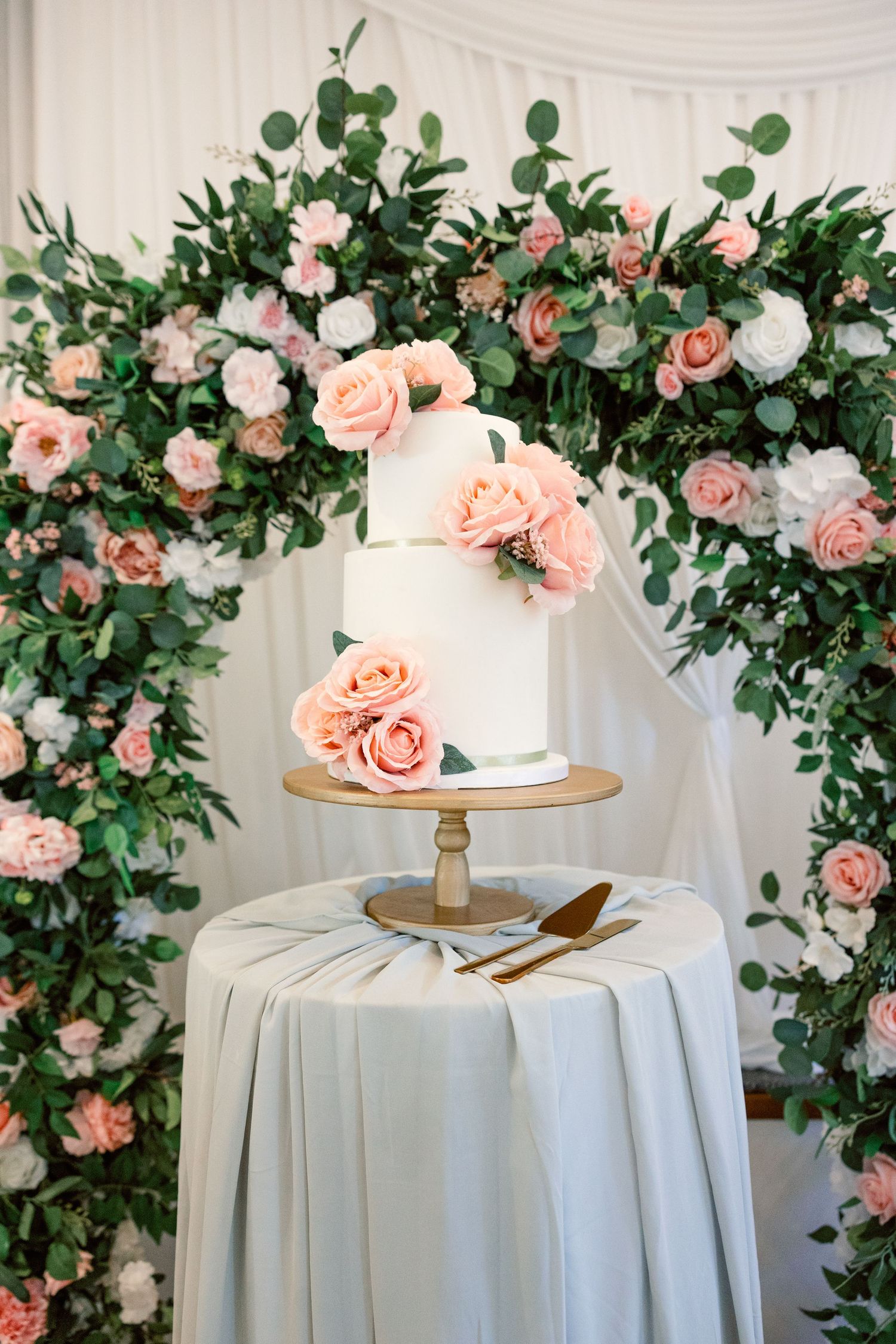 White tablecloths adorned with pink and white roses create an elegant wedding reception setting.