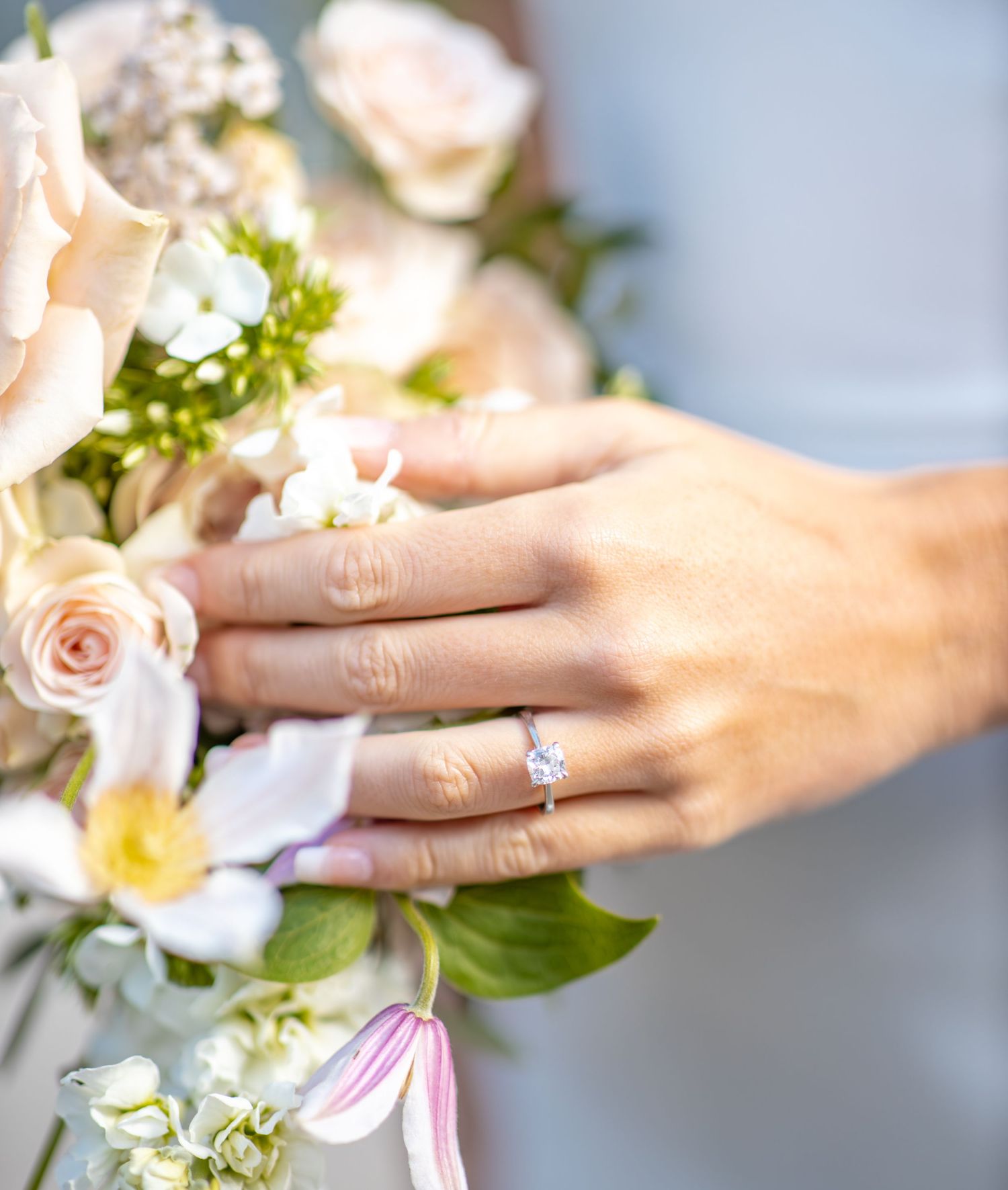 Close-up of engagement ring with white floral bouquet.