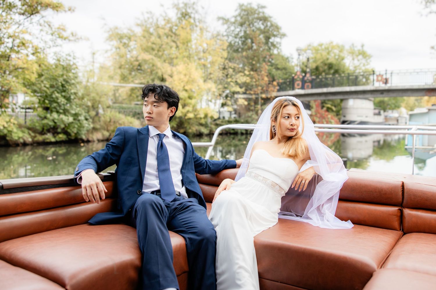 Newlyweds relax on brown leather seating during outdoor wedding photography.