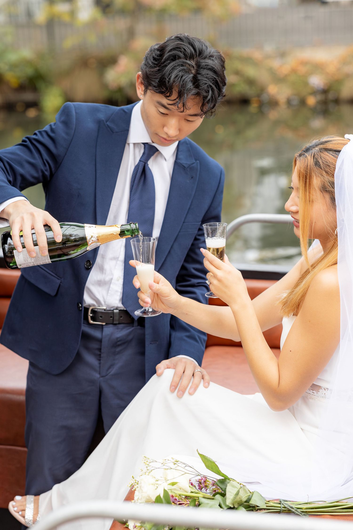 Newlyweds share champagne and laughter during their outdoor wedding celebration.
