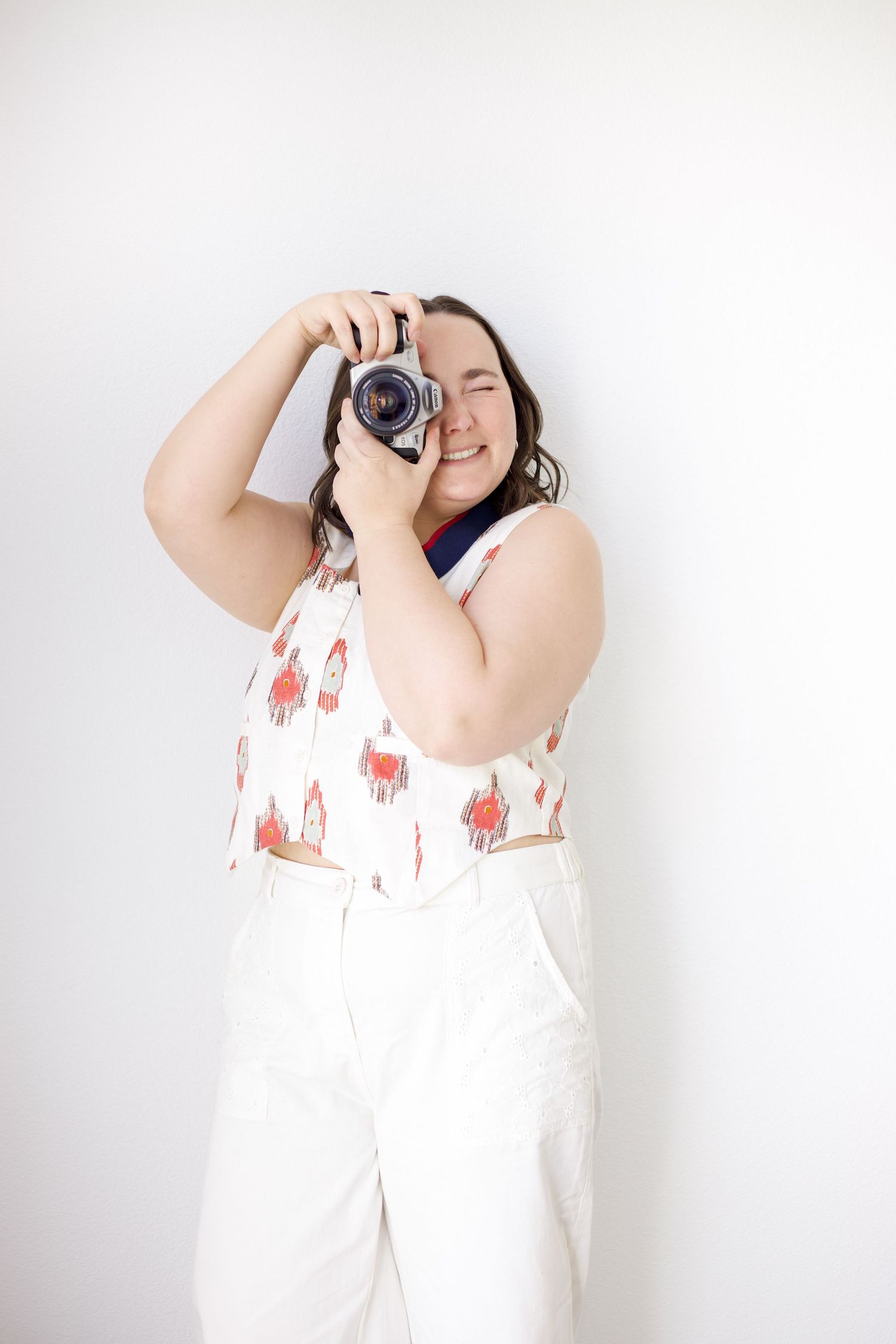 Playful poses with a vintage camera against white studio backdrop.