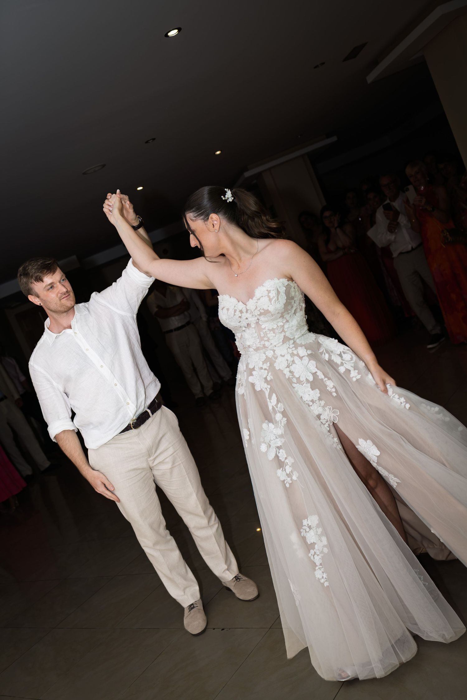 Bride and groom share first dance as groom spins bride in floral wedding gown.