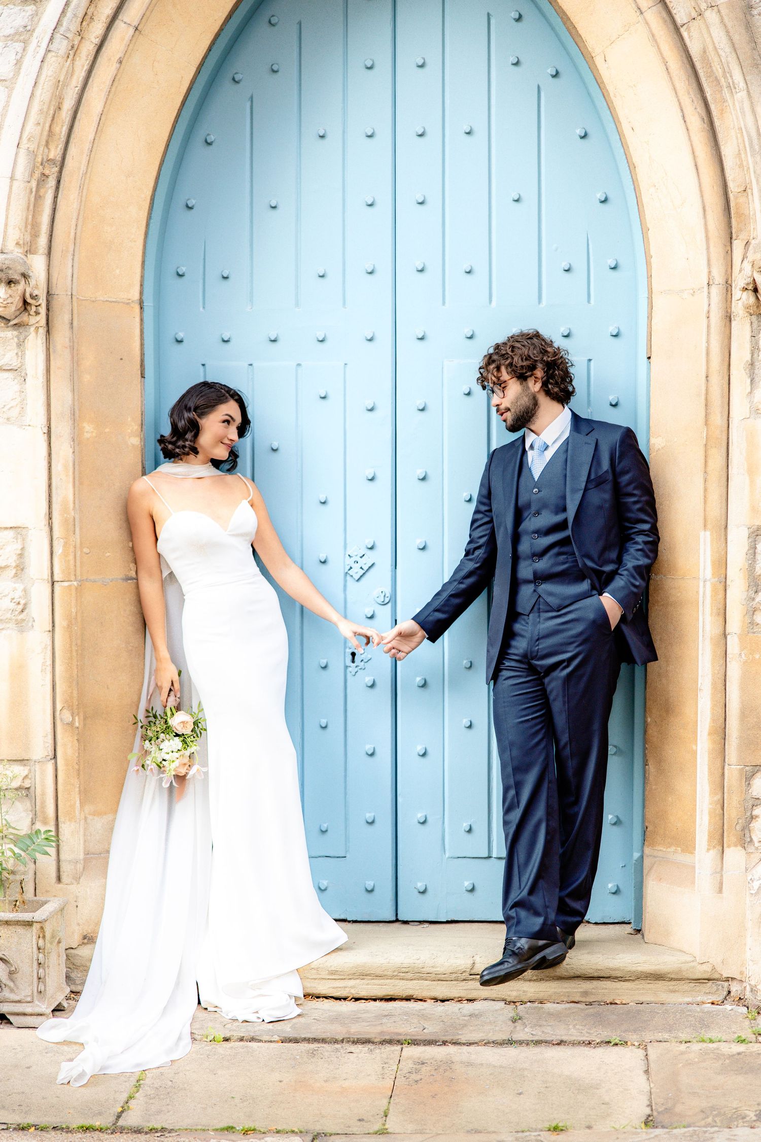 Wedding photo series in front of large blue church door showing playful couple poses.