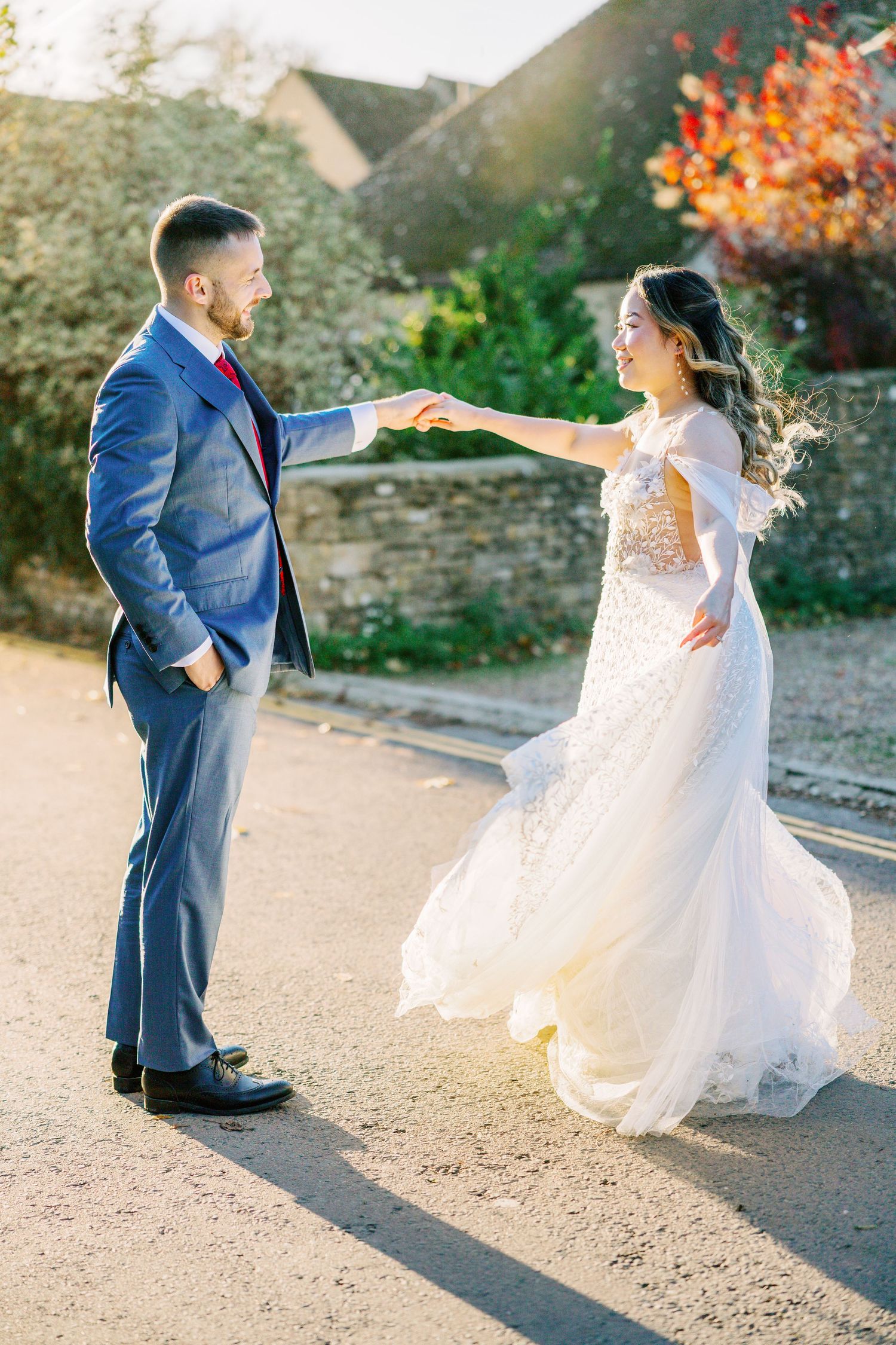Wedding couple dances playfully on a stone path during sunset.