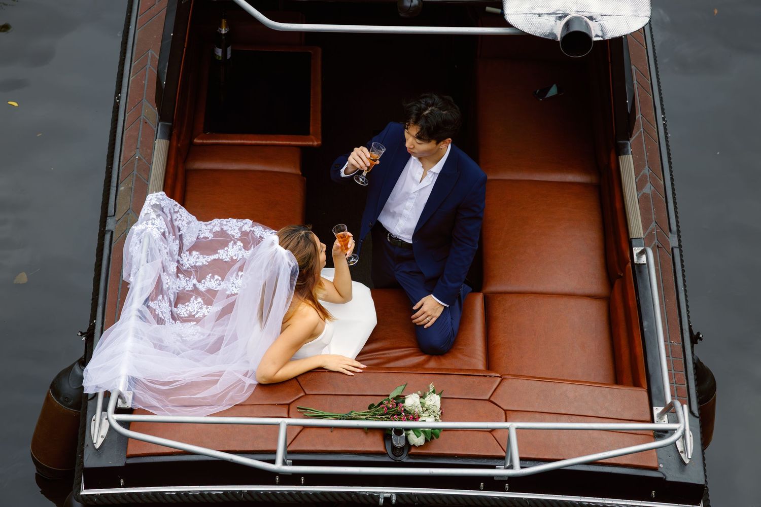Person in a white dress lying on a metal hospital bed while being wheeled down a hallway.