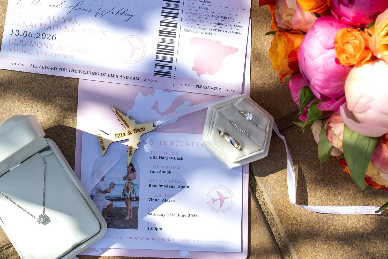Wedding stationery with boarding pass invitations, diamond ring box, and colorful floral bouquet arrangement.