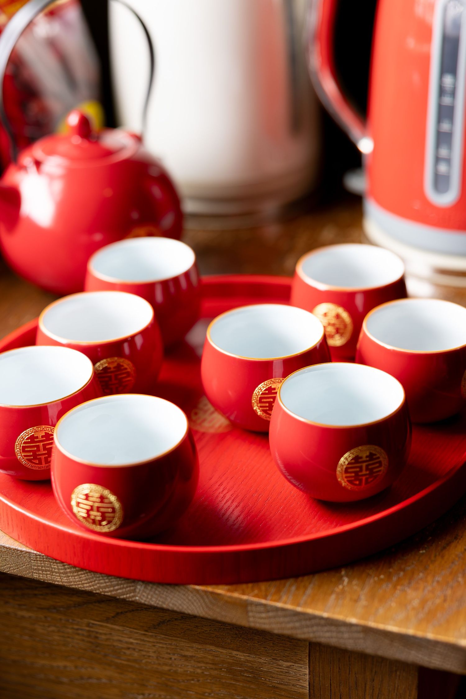 Traditional red Chinese wedding tea ceremony set with gold double happiness symbols on a round tray.
