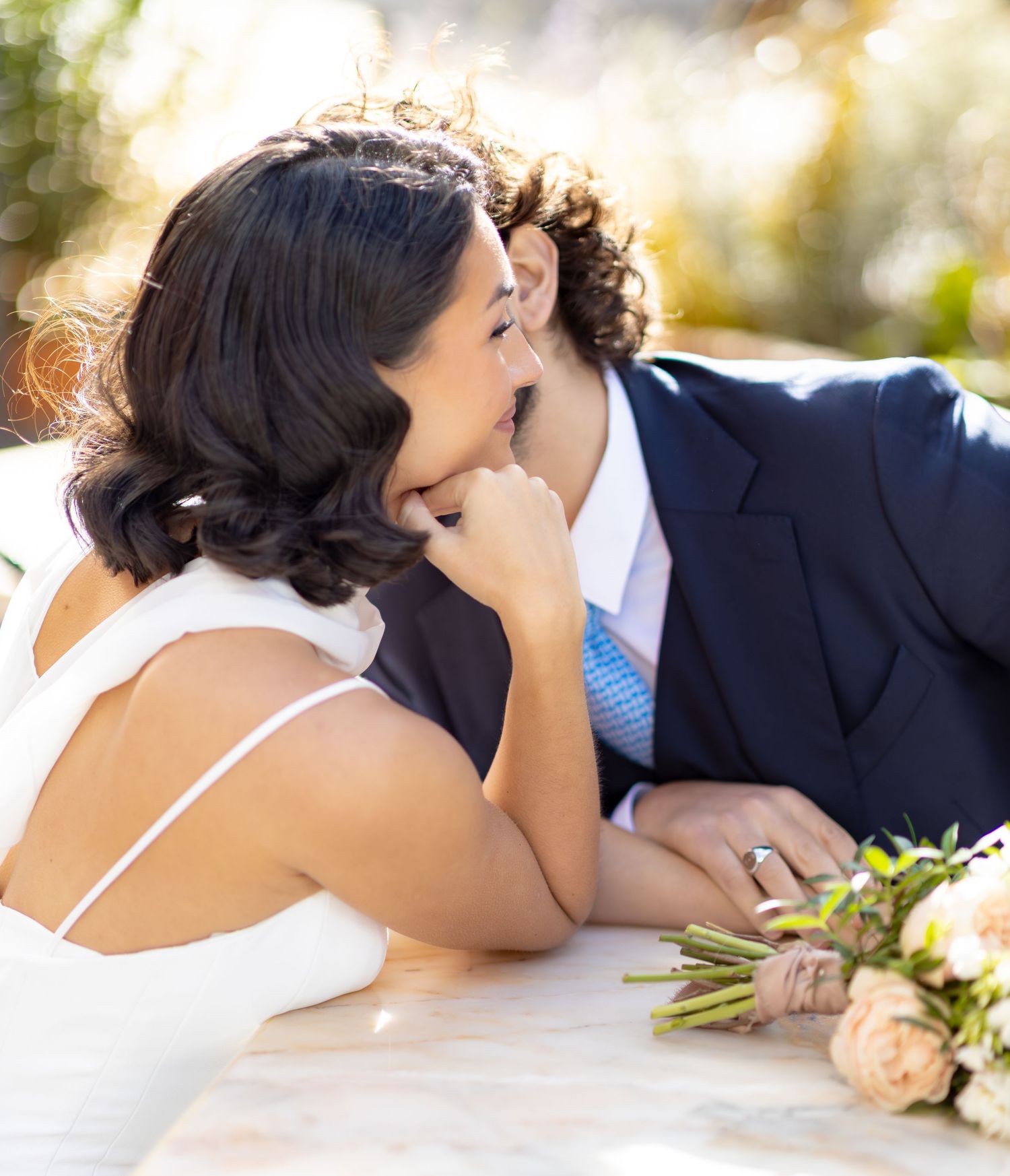 Newlyweds share a tender moment while reclining together outdoors.