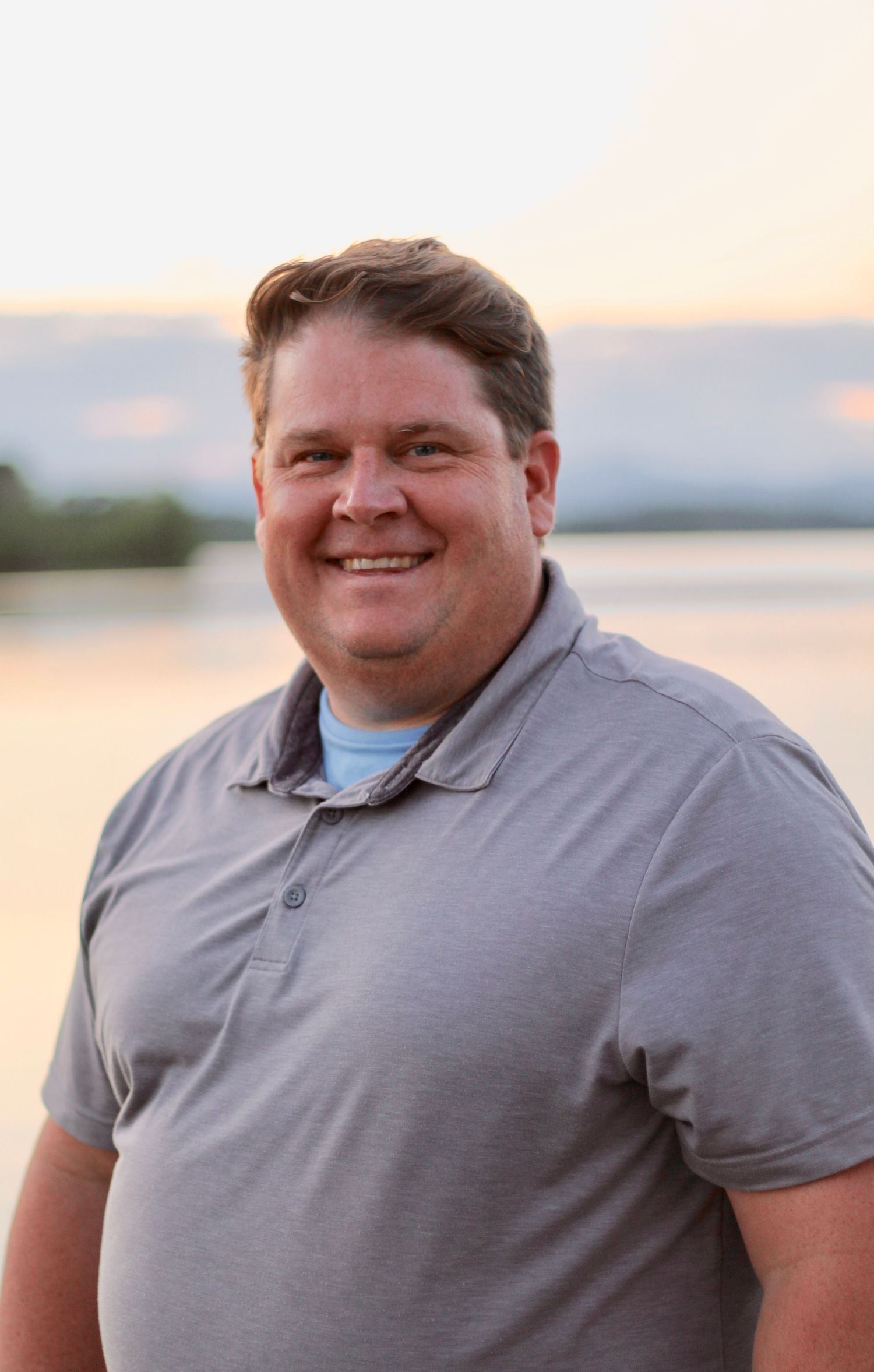 Daddy smiles at the camera with a sunset in the background.