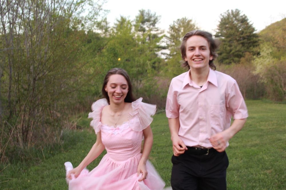 A couple decked out in pink runs towards the camera.