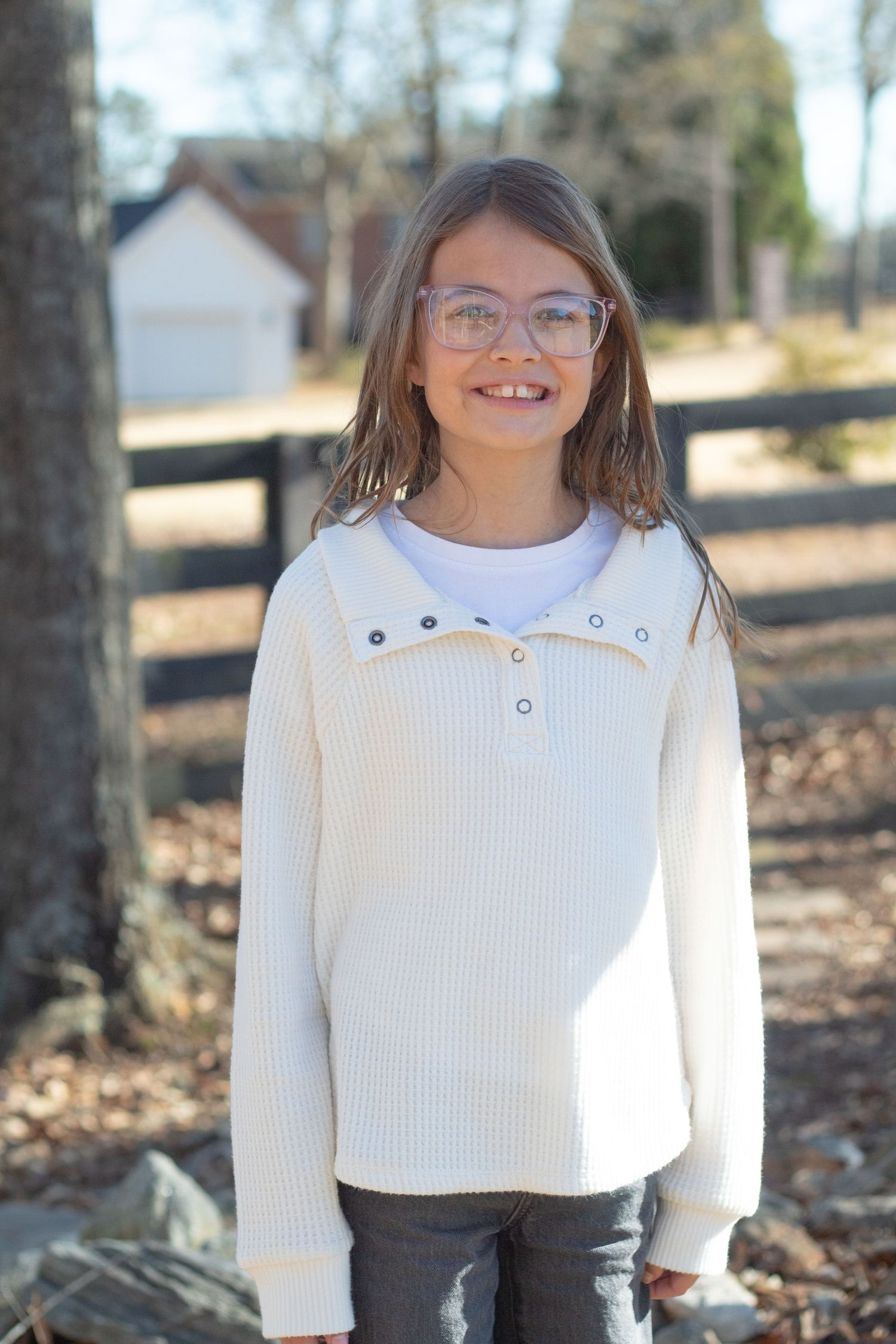 White-sweatered young lady smiling at the camera.