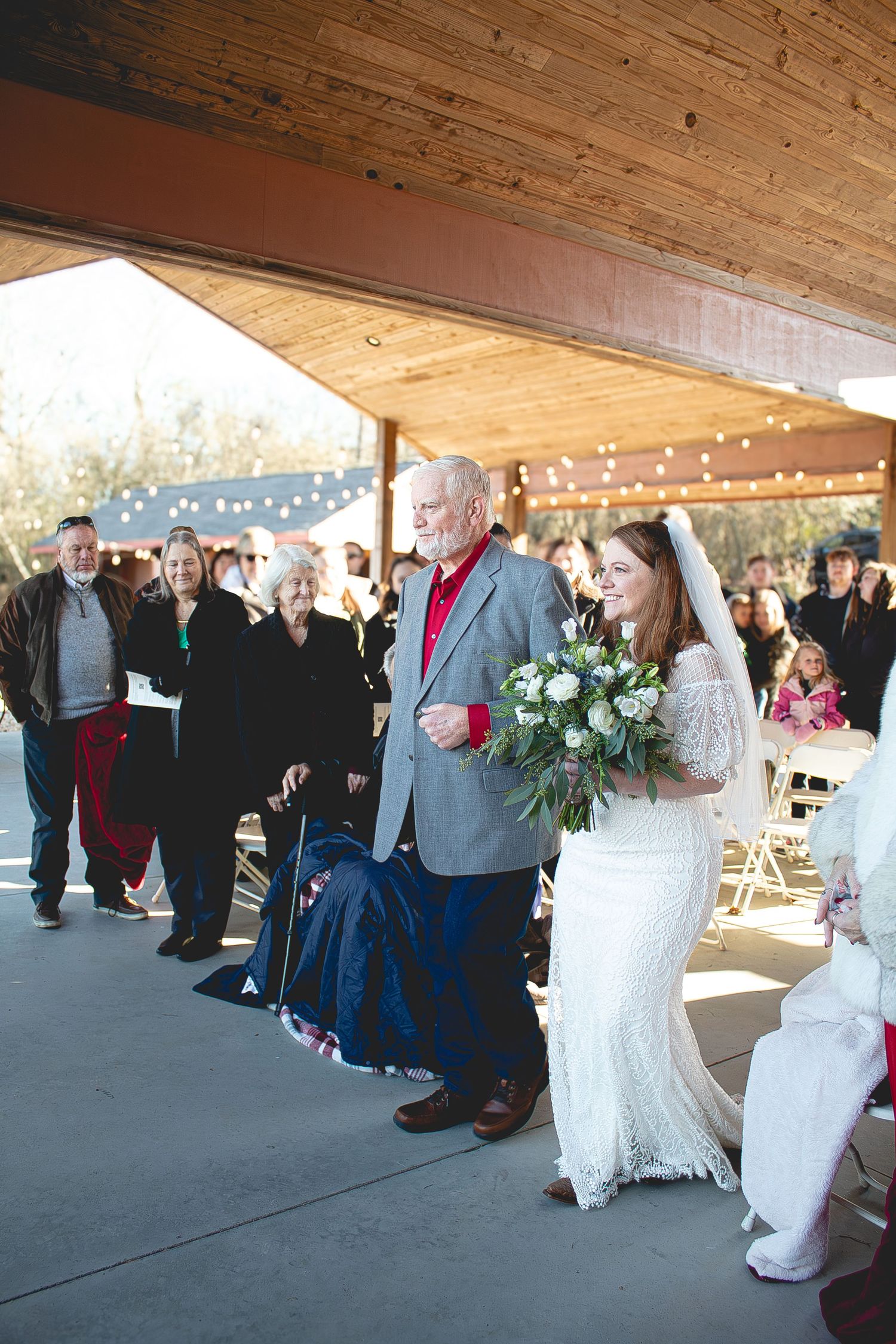 Bride and her dad have just approached the top of the aisle, as her groom looks on lovingly.