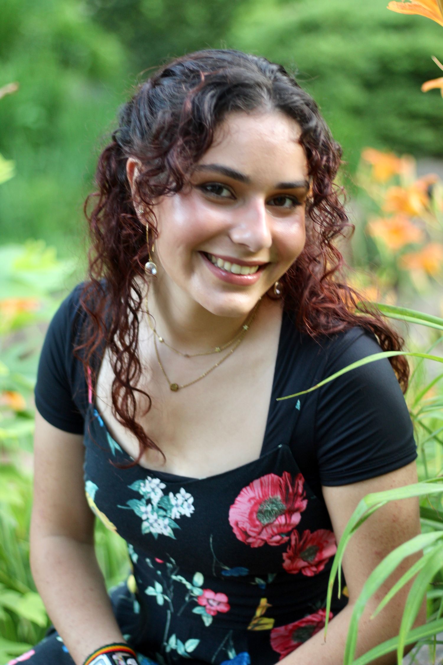 Nestled in a field of flowers, she smiles up at the camera.