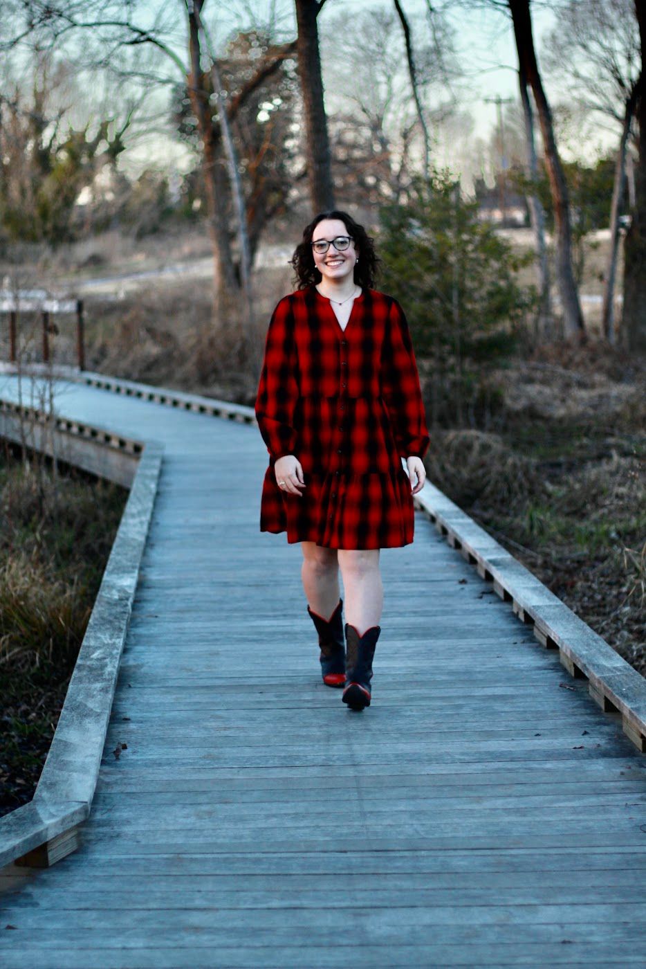 A senior girl walking in a plaid dress on a boardwalk in Unity Park, downtown Greenville.