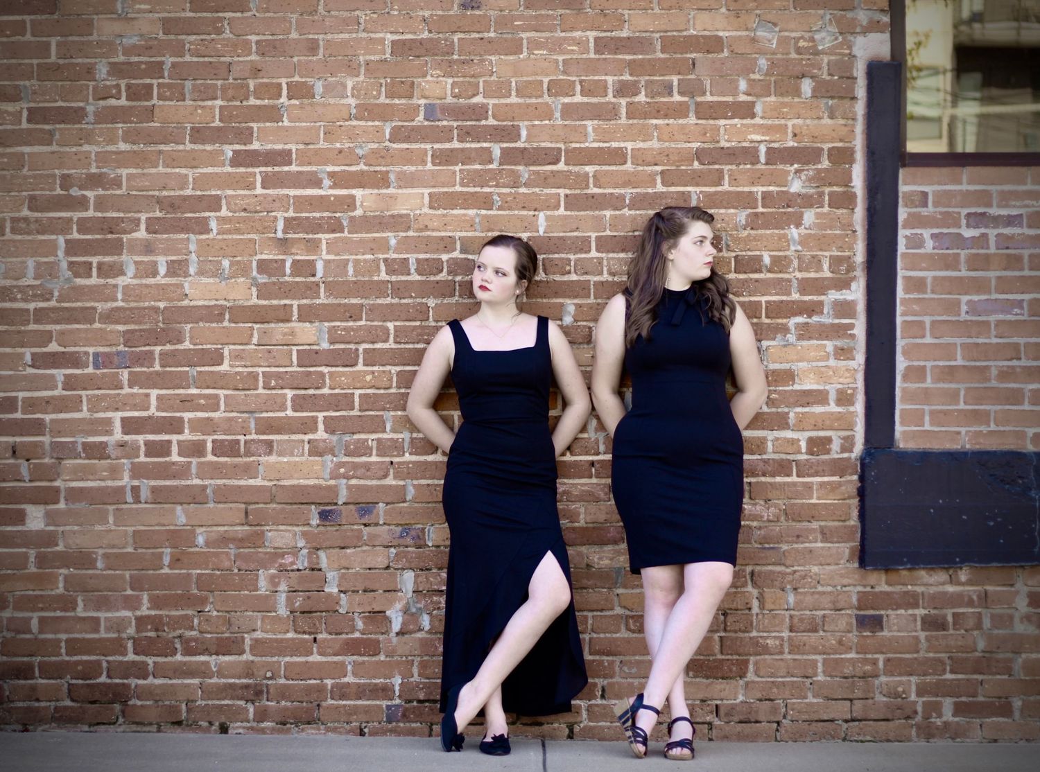 Girls power pose in front of a brick wall.