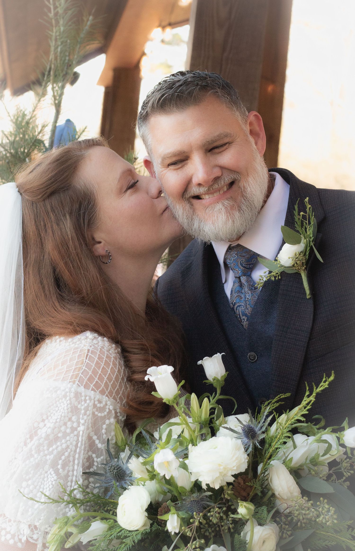 Bride smooching the groom's cheek.