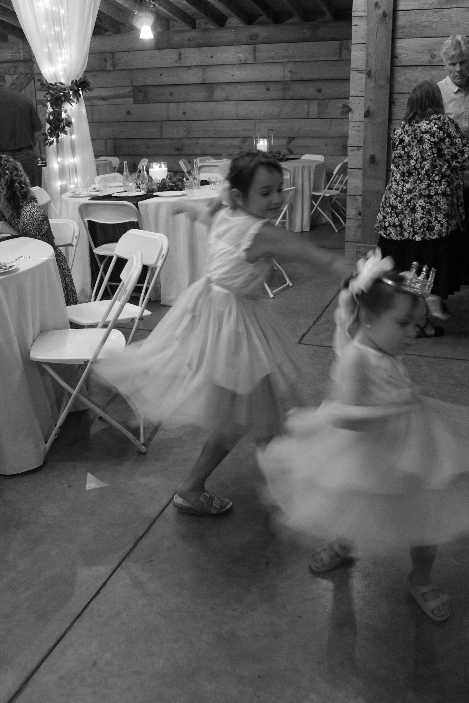 Twirling each other, two little girls have fun at a wedding reception.