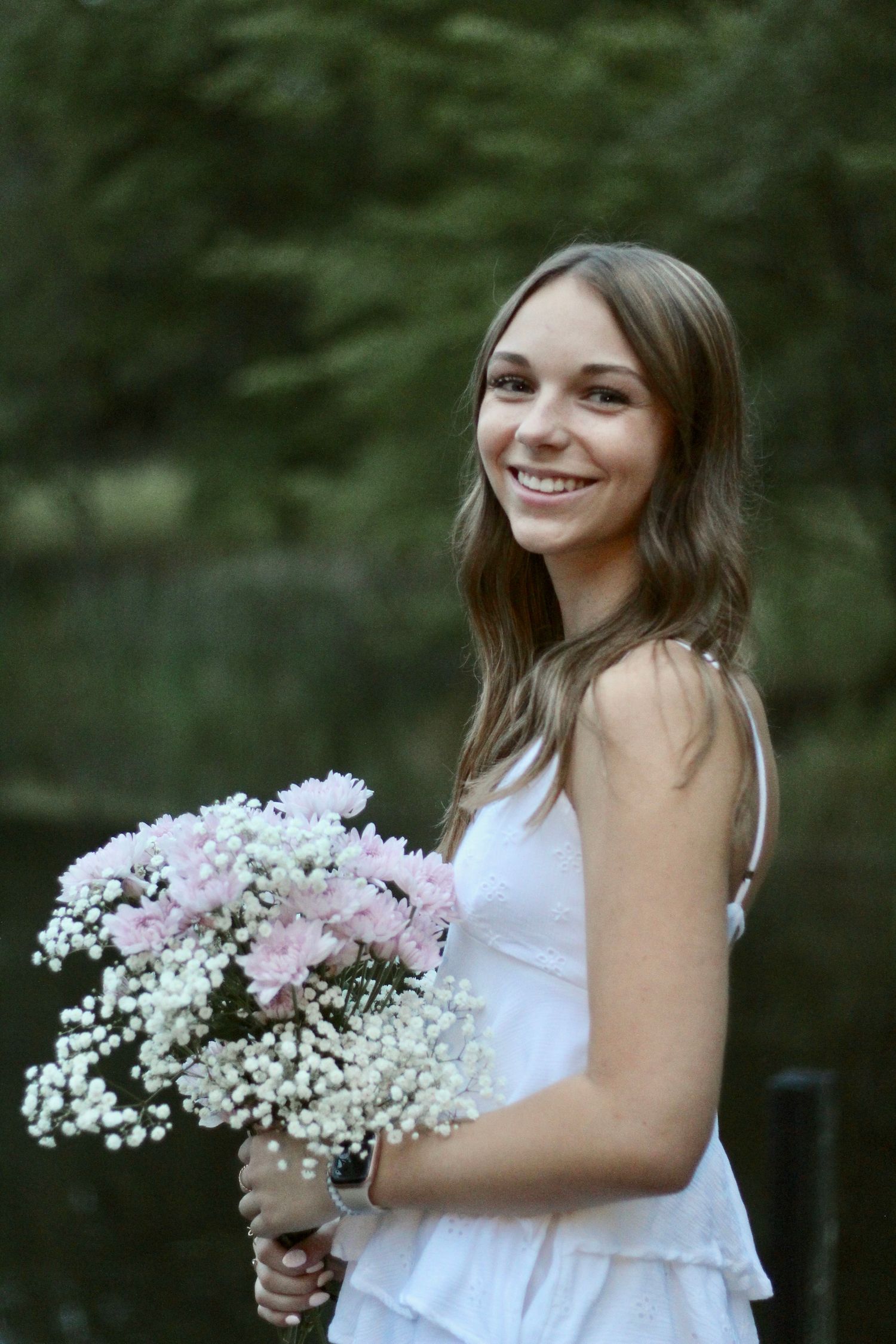 She's holding her bouquet as she smiles at the camera.