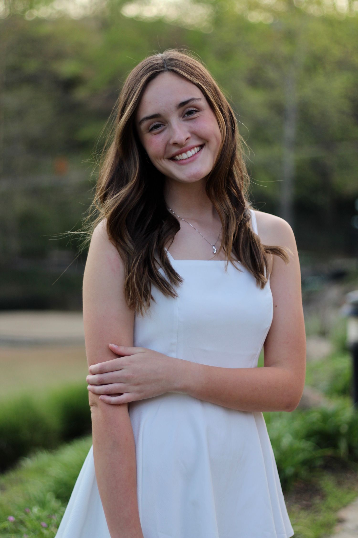 A girl in a white gown smiling at the camera.