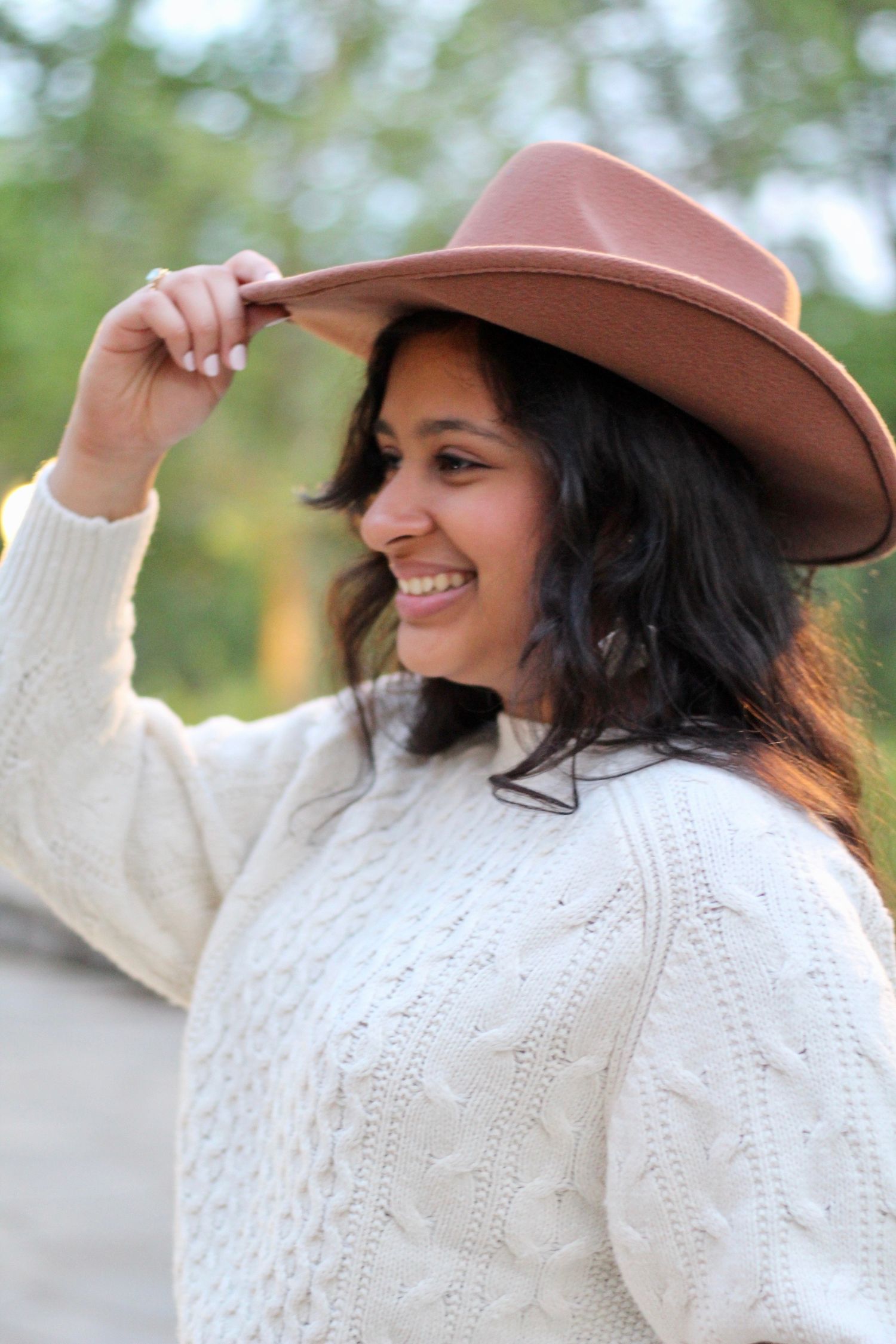 Holding her cowboy hat, she smiles towards the future.