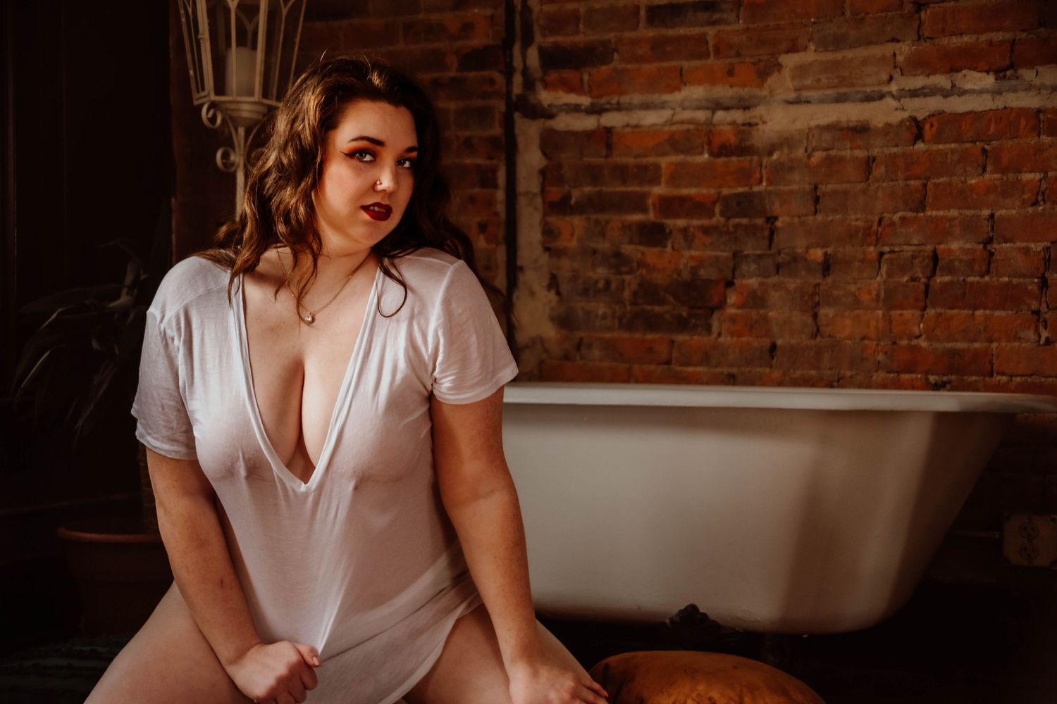 Lifestyle portraits in a rustic brick-walled setting with soft window lighting.
