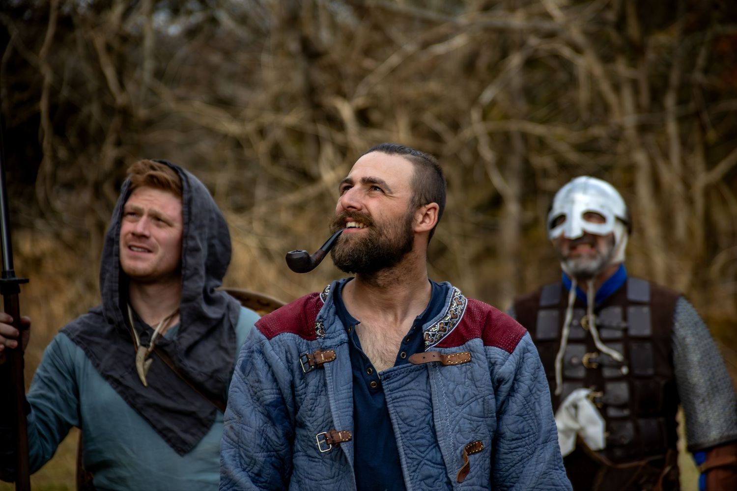 A group of people laugh together while enjoying an outdoor gathering in casual winter attire.