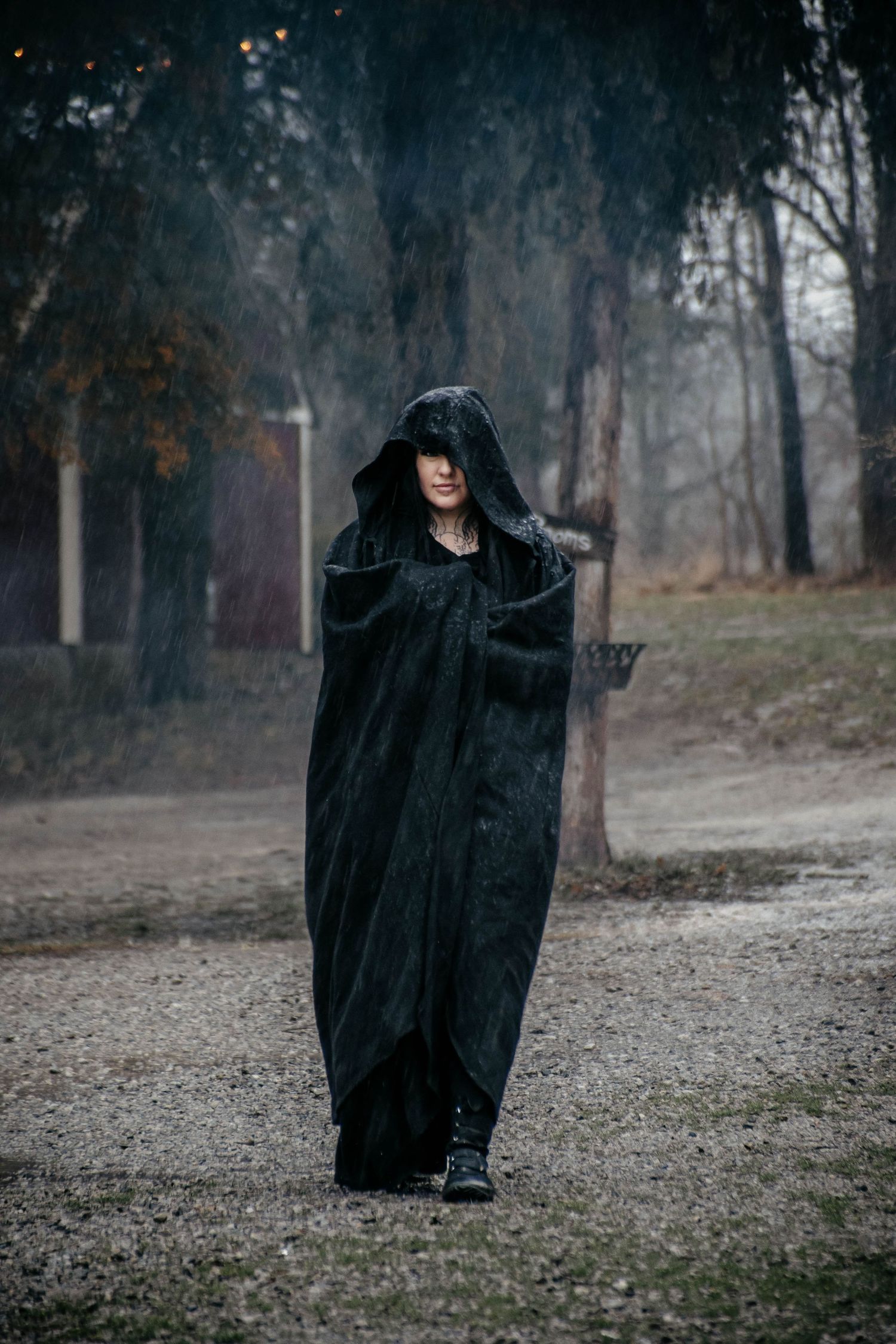 A mysterious figure in a black cloak moves through a misty forest path in a series of dramatic poses.