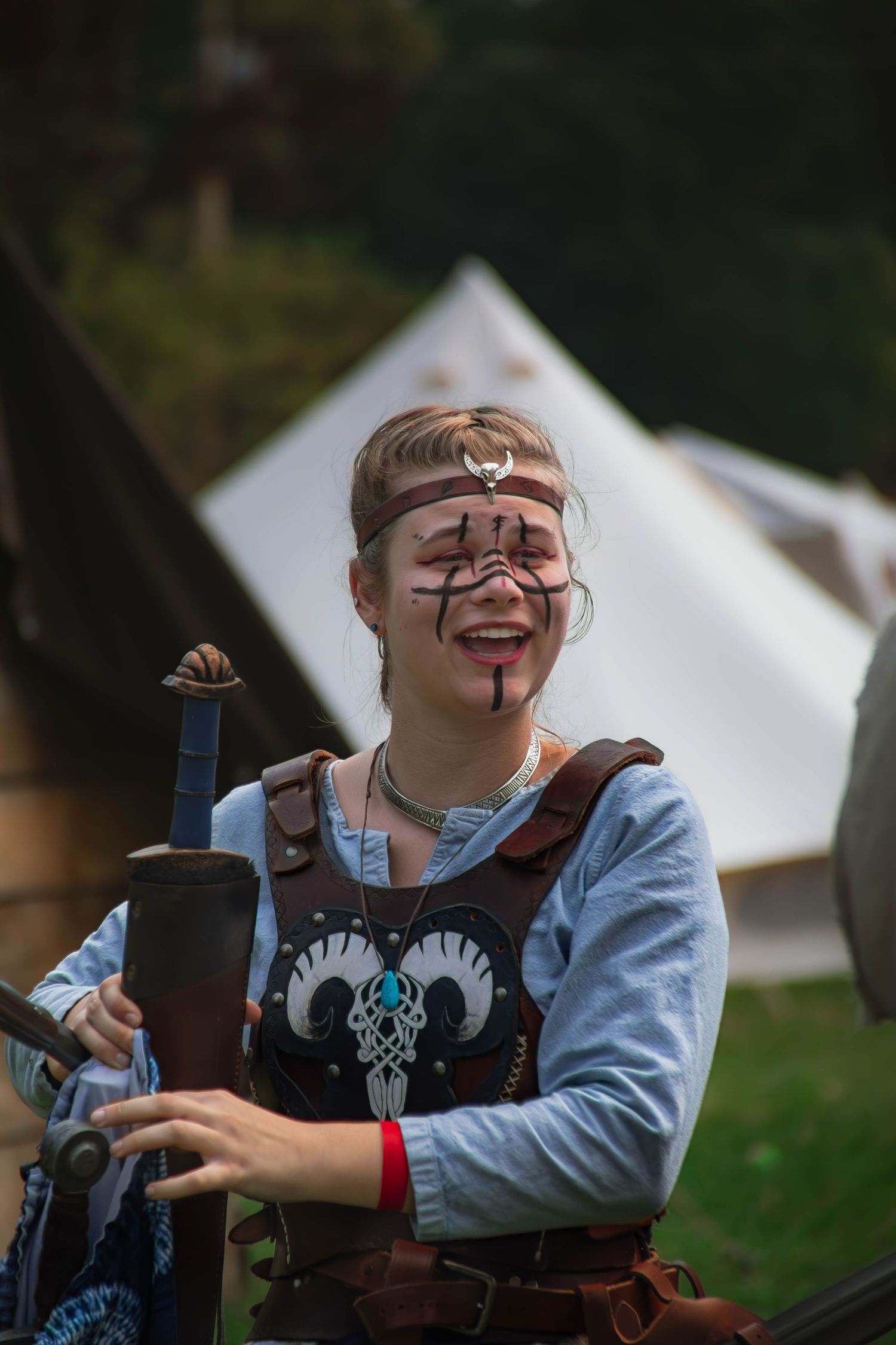 A sequence of photos showing someone in medieval costume laughing while holding a wooden object at a renaissance fair.