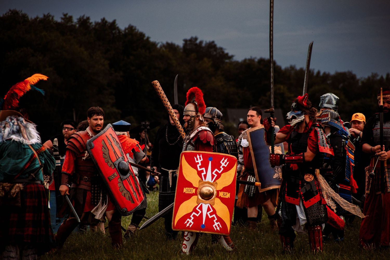 Medieval battle reenactors clash with swords and shields at dusk during a historical combat demonstration.