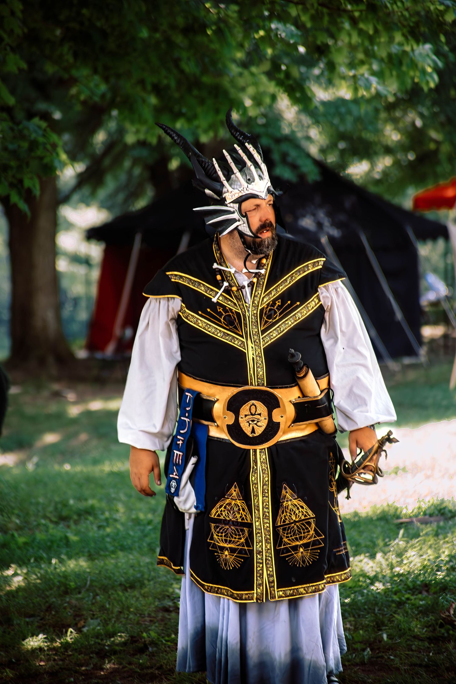 Traditional folk costumes featuring ornate black vests with gold embroidery and white sleeves displayed in an outdoor setting.