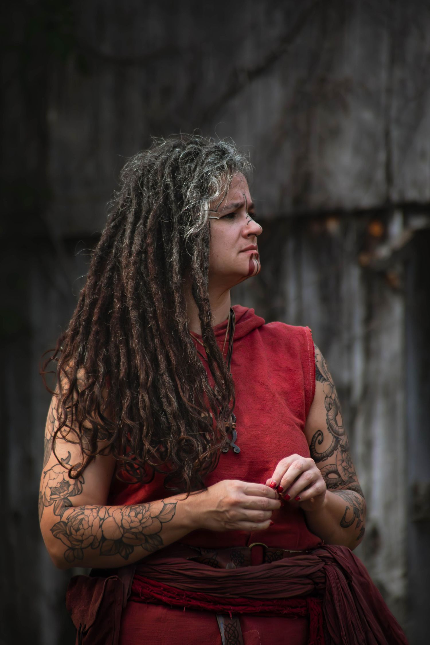 Moody portrait featuring curly hair and a red garment against a dark background.