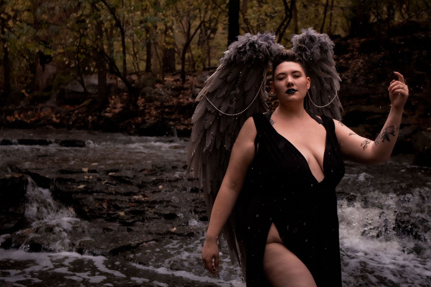 Dramatic black and white portrait near stone wall with flowing water.