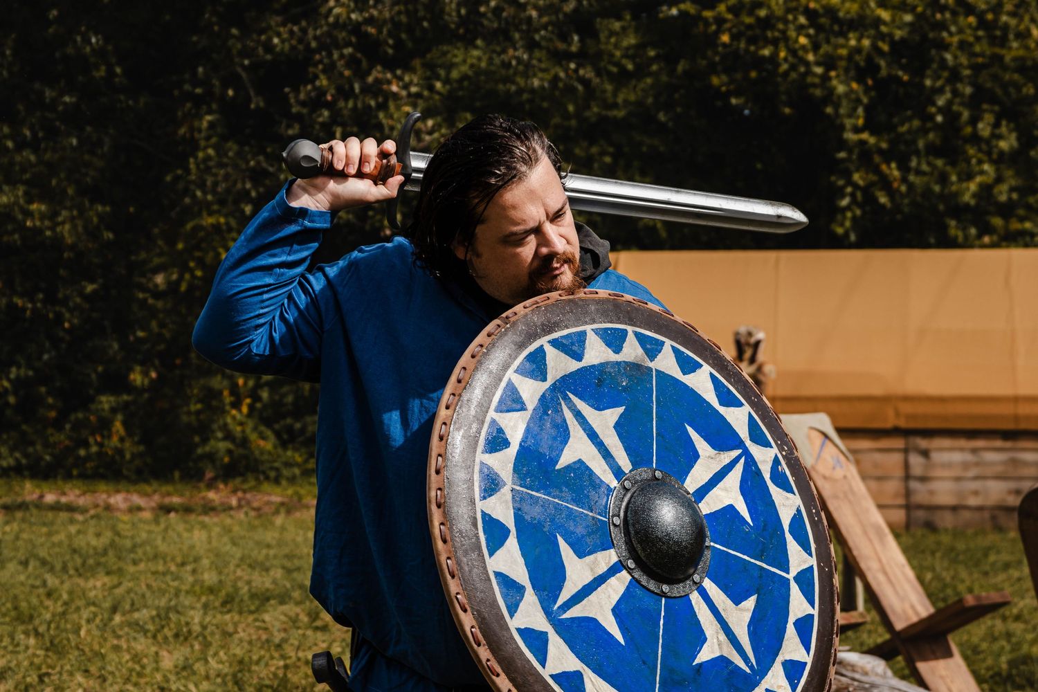 Viking-style shield with blue and white geometric patterns displayed outdoors.