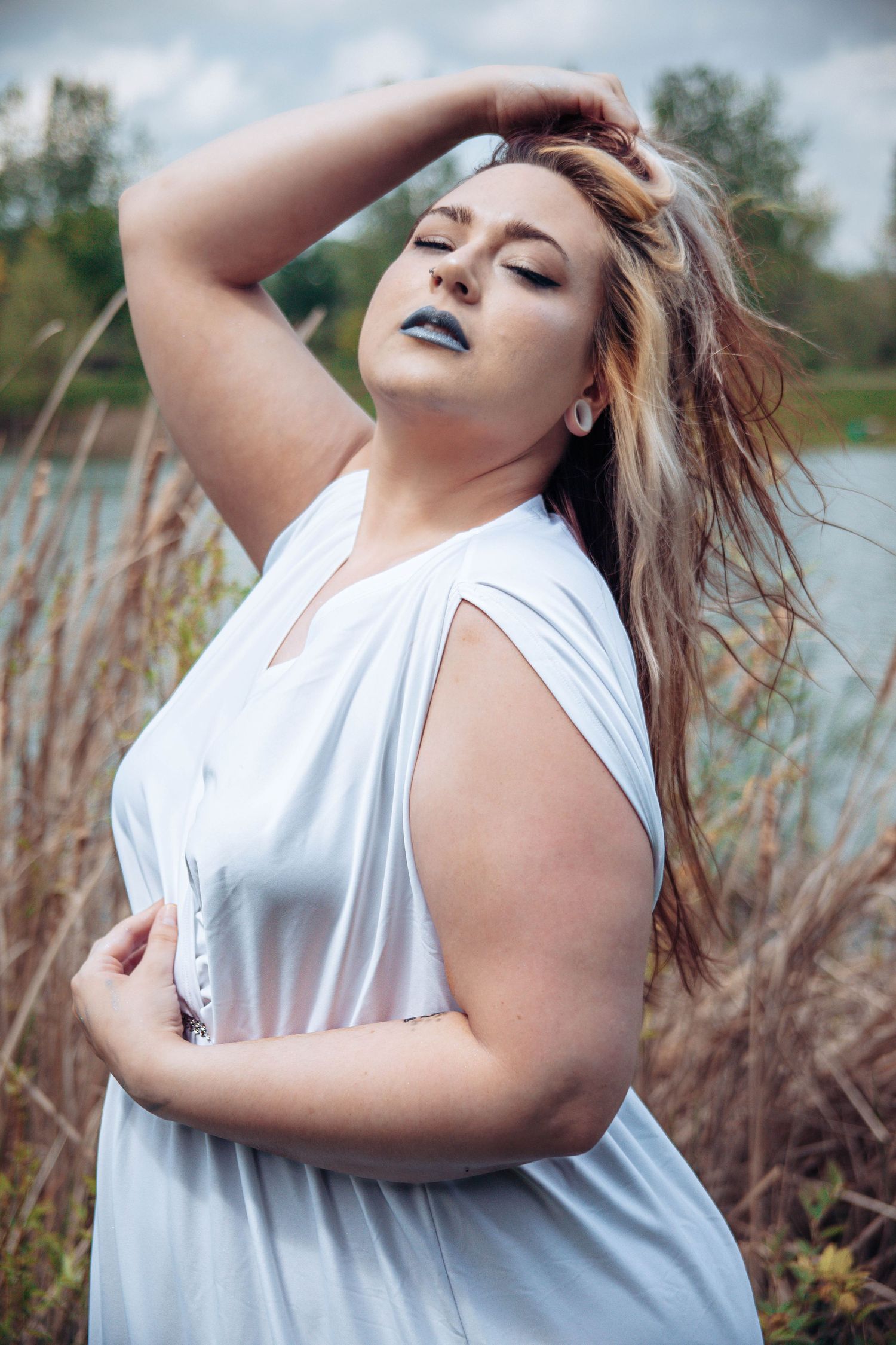 Artistic outdoor portrait session in white clothing with dramatic blue lipstick.