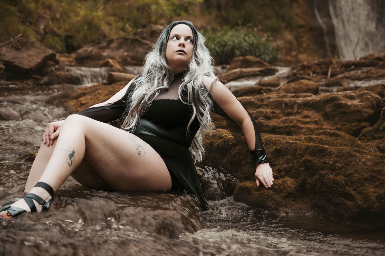 Artistic outdoor portrait with silver hair against natural rock formations.
