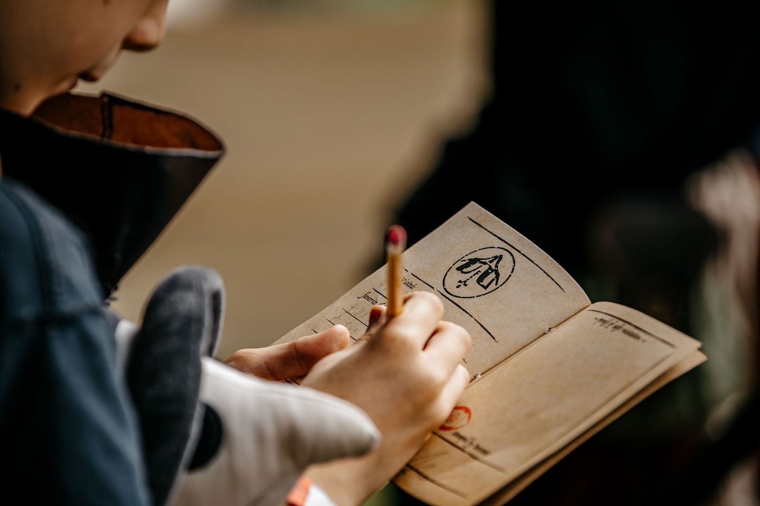 Child reading a small illustrated booklet outdoors, holding it open with both hands in natural light.