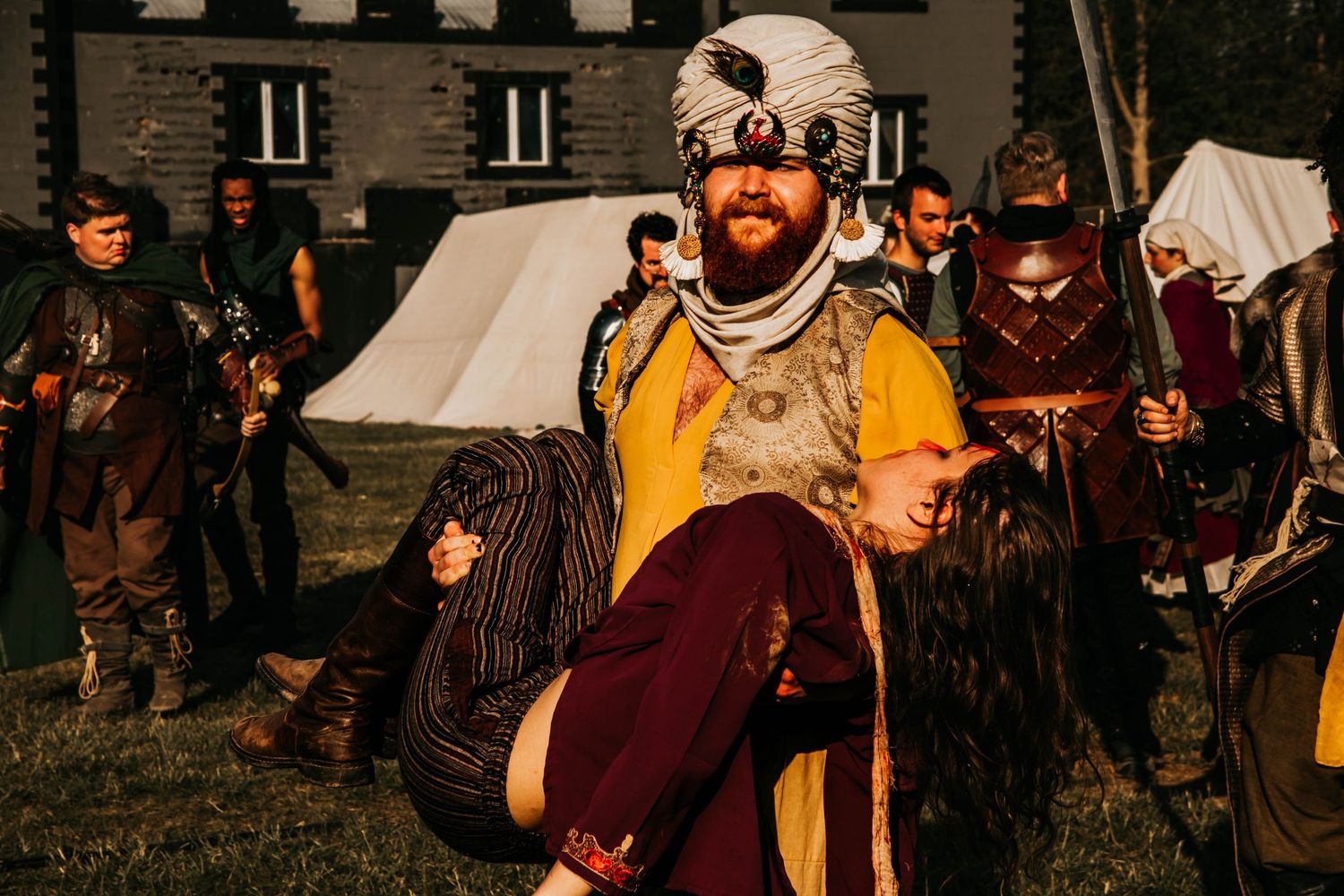 Medieval reenactors in period costumes gather outdoors during a historical event.