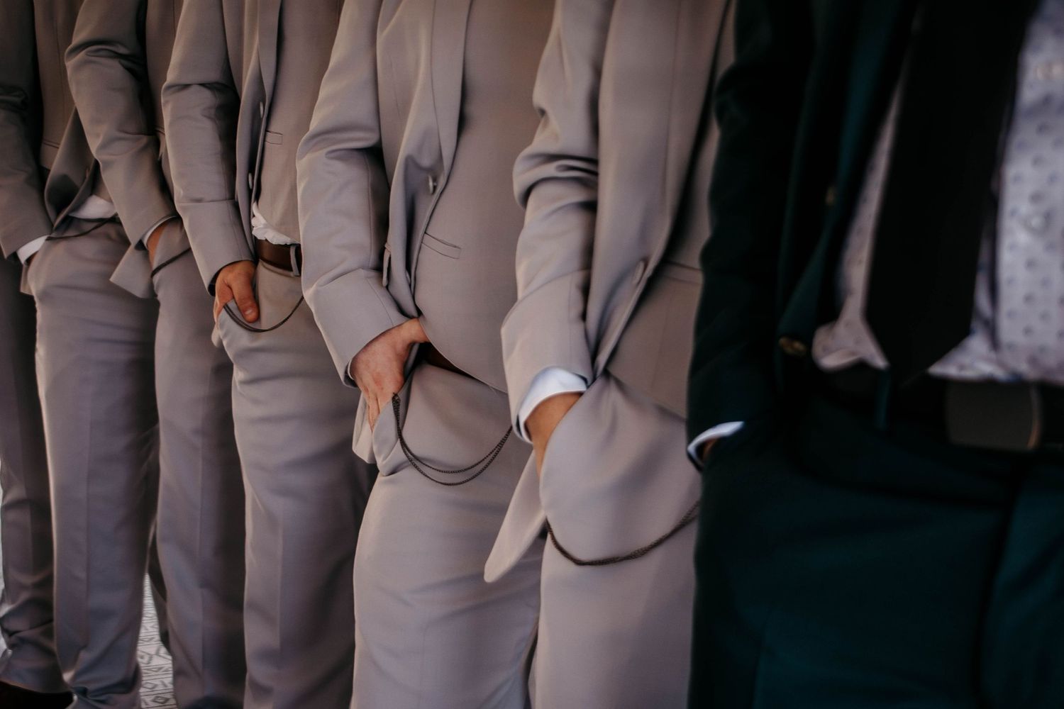 Row of groomsmen in matching gray suits at formal wedding.
