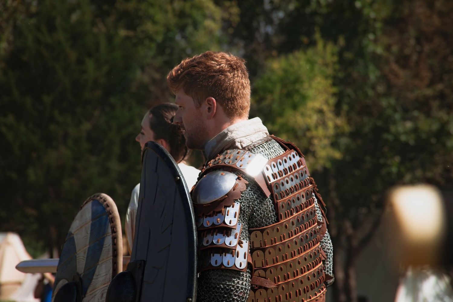 A couple in winter sweaters shares a tender moment outdoors during golden hour lighting.