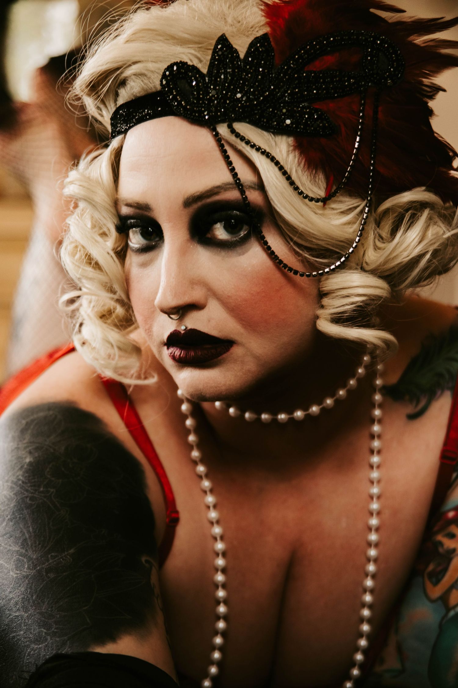 A dramatic portrait series showing theatrical makeup with pearls and black feather accessories in moody lighting.