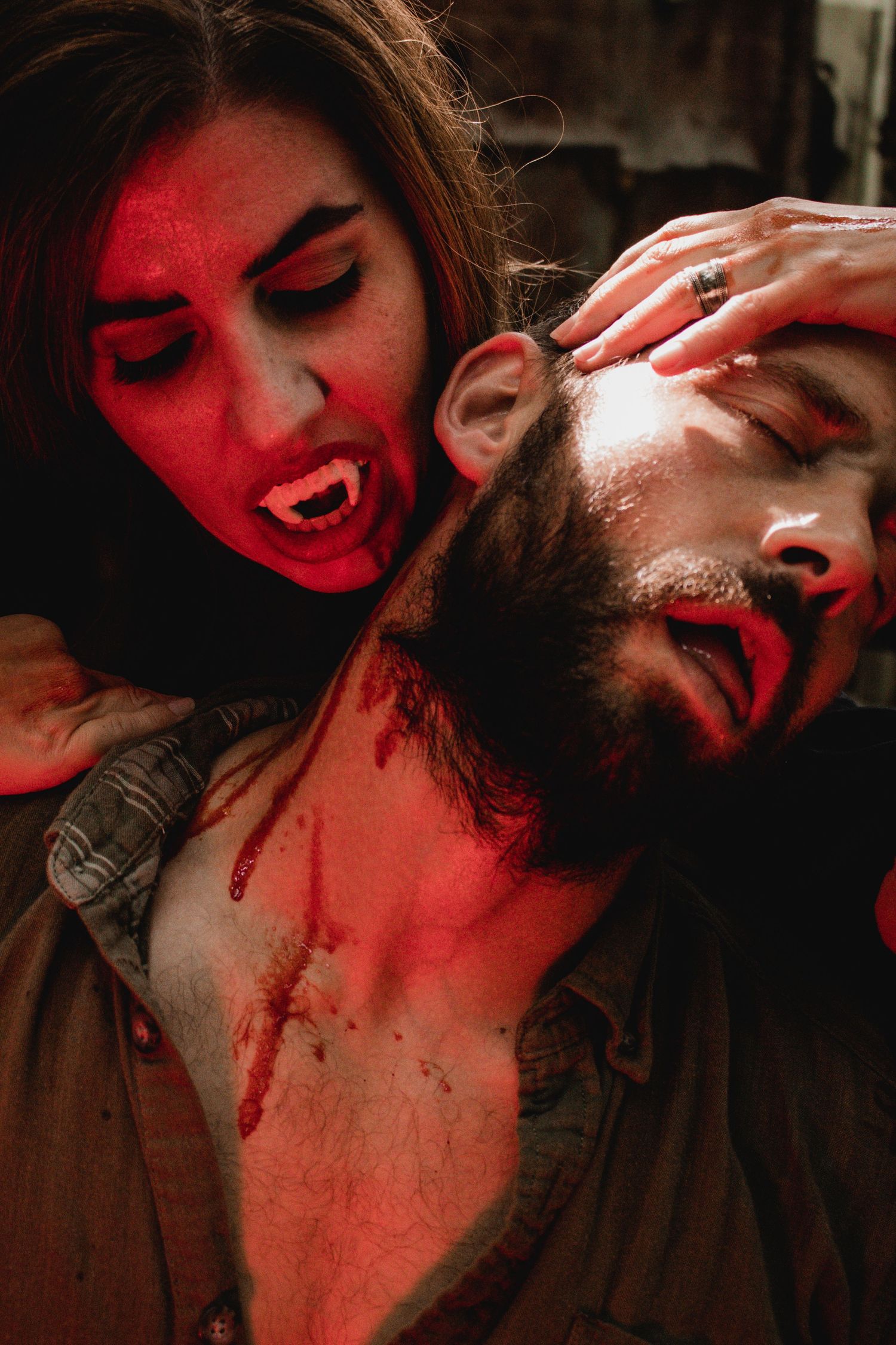 A series of intimate romantic photos with dramatic red lighting shows a couple embracing in shadow.