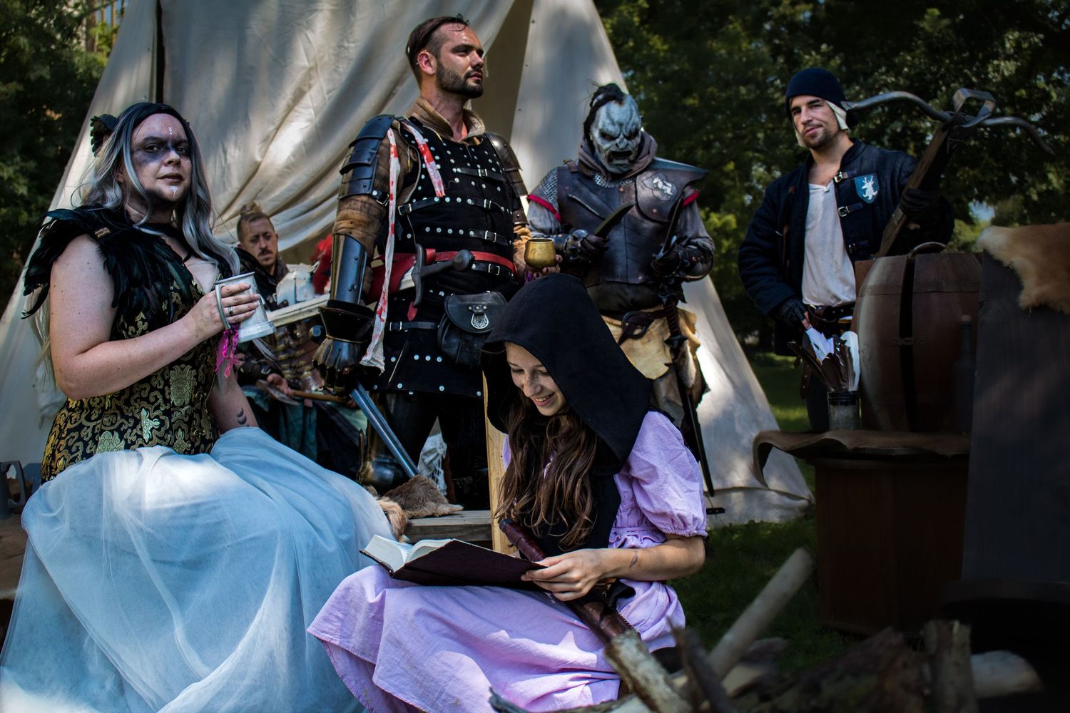 Cosplayers in colorful outfits pose together at an outdoor convention or gathering in a park setting.
