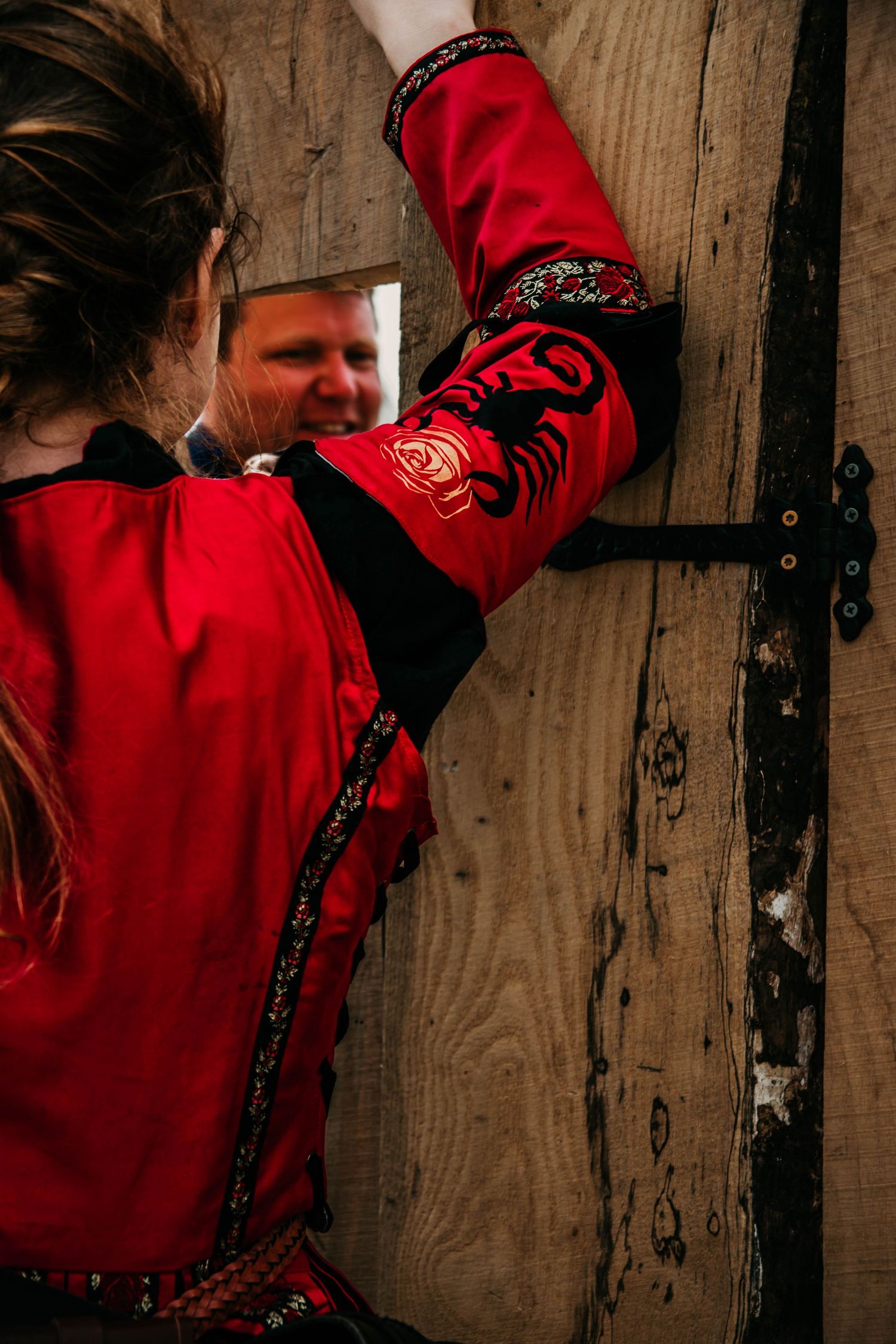 Person in red jacket and black hat reaching up to touch rustic wooden wall panels in dramatic lighting sequence.