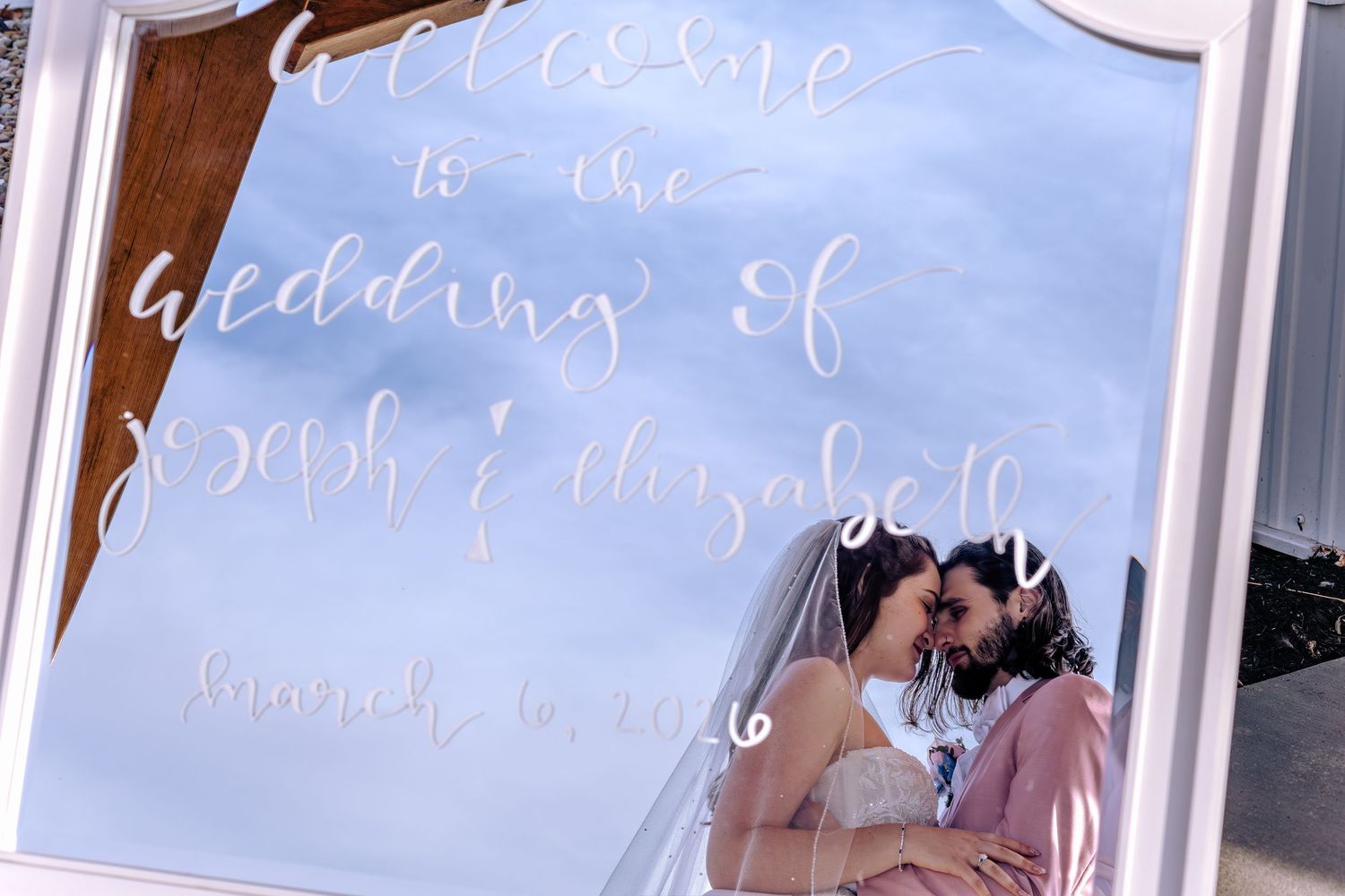 Wedding decor features elegant white calligraphy text on light blue signs displayed at a reception venue.